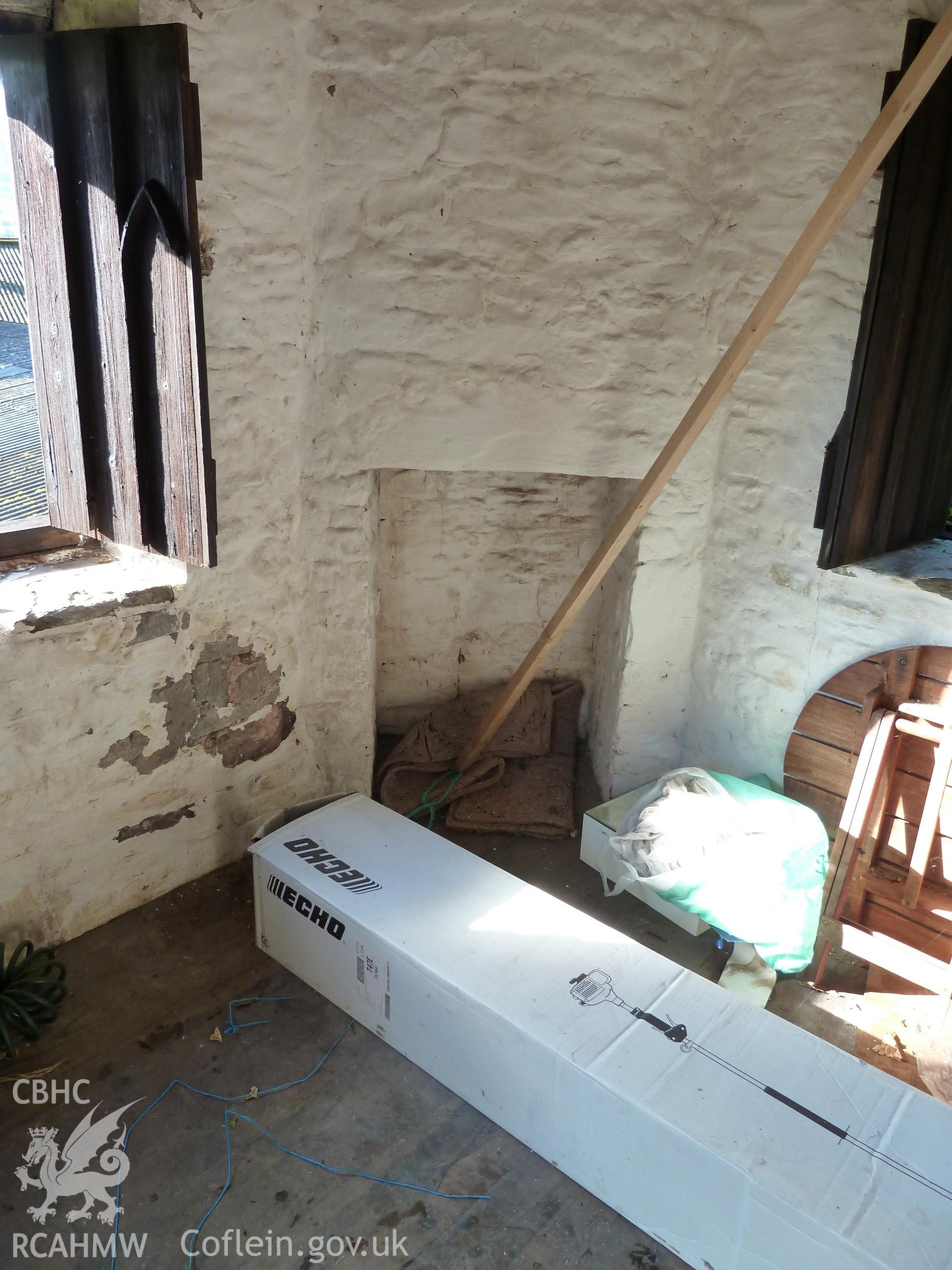 Internal view showing corner hearth, flanked by unglazed - shuttered - window openings.