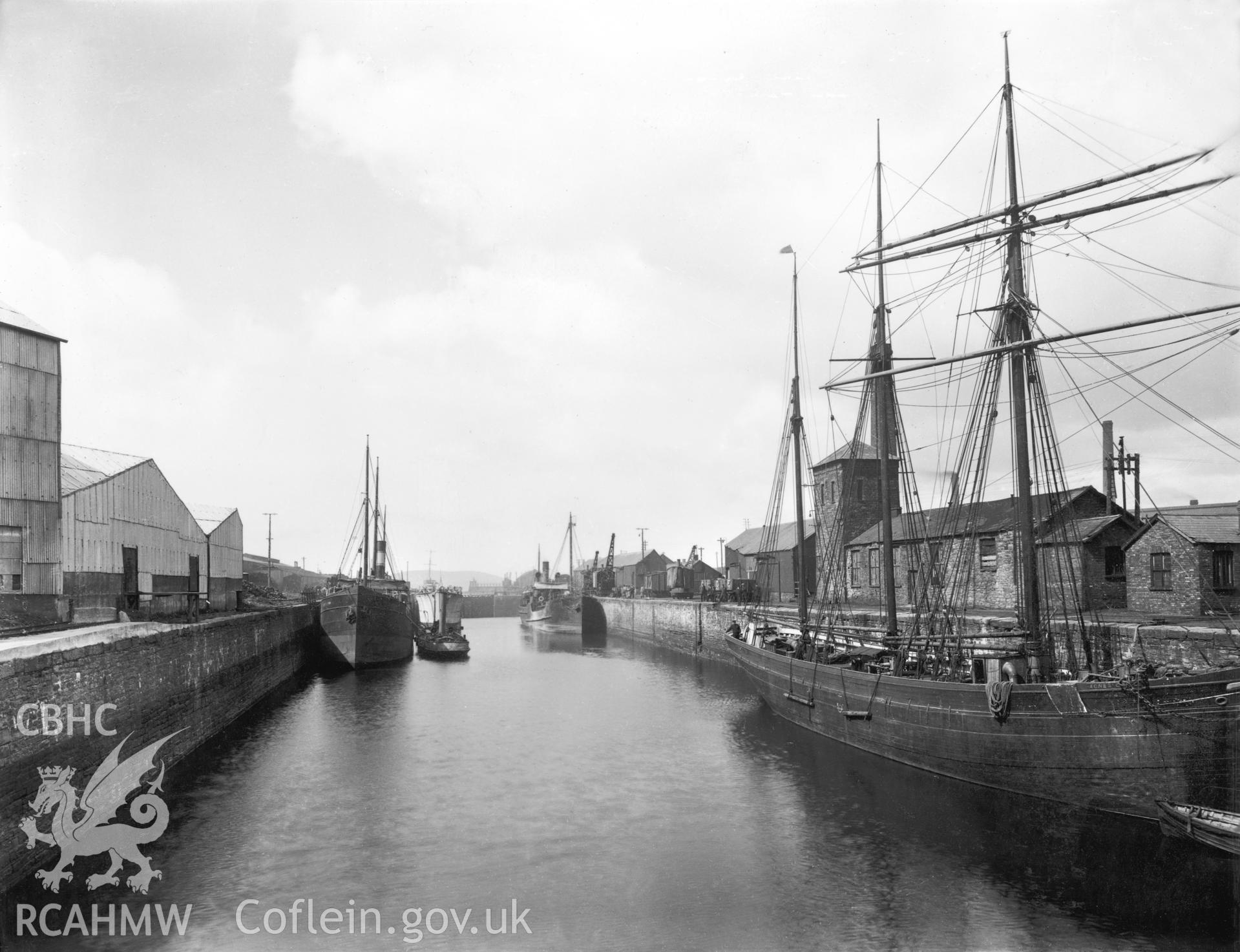 Black and white photograph showing three masted sailing barque alongside the quayside in Copperdock, Llanelli (steam coasters in the background).