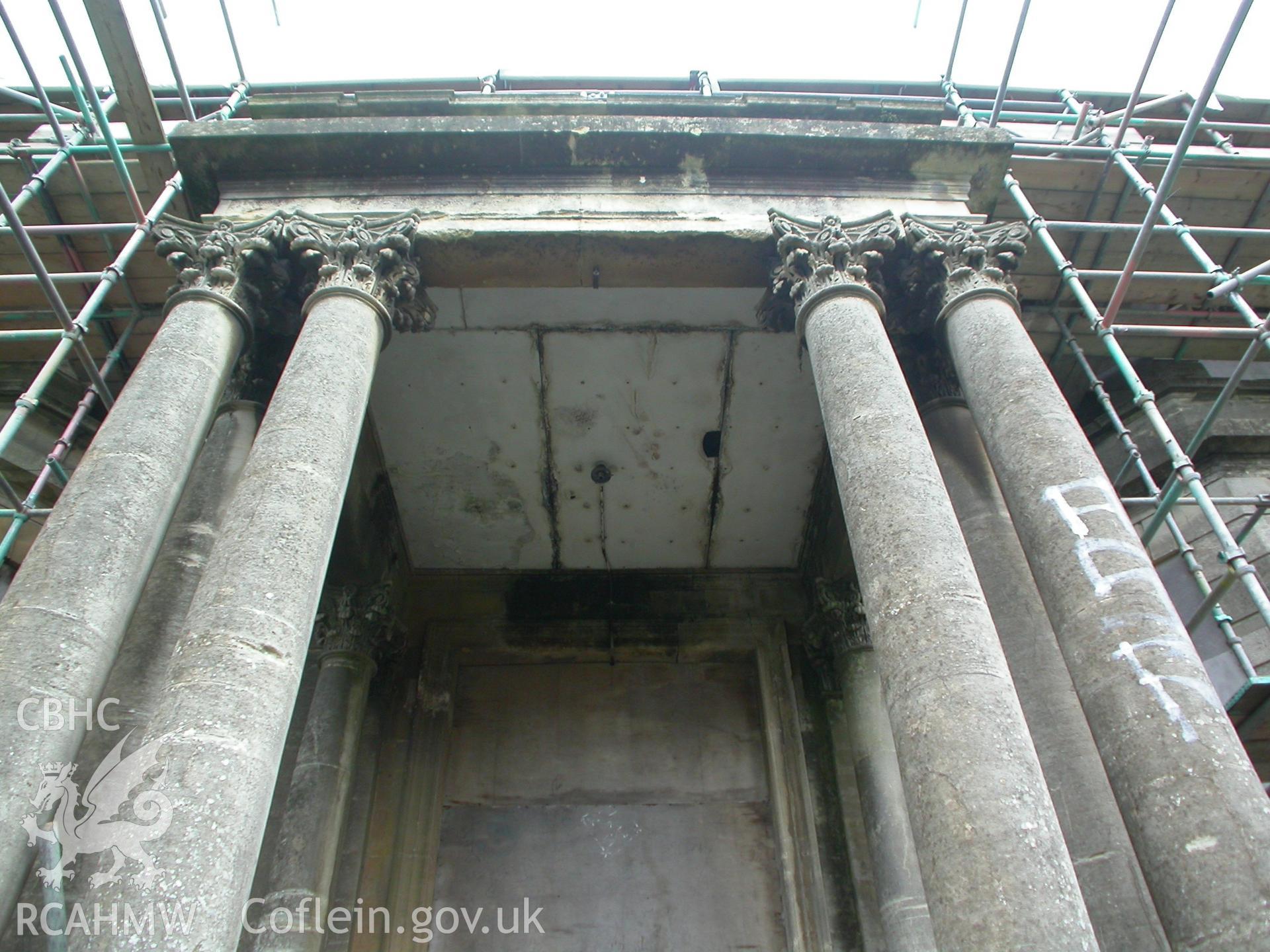 Flat roof of porch with entableture and parapet, supported by columns with carved foliate decoration of the Corinthian Order.