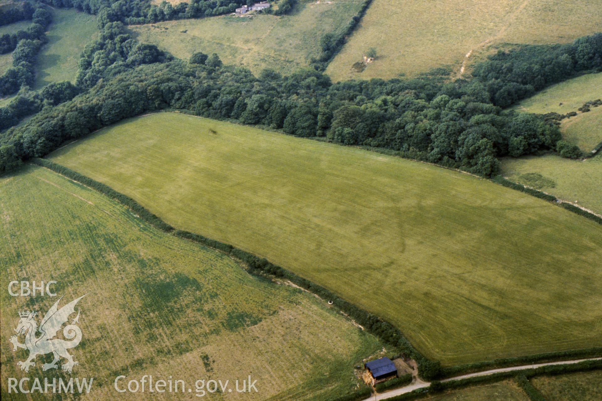 Slide of RCAHMW colour oblique aerial photograph of Pen Cnwc Cropmark Enclosure,  taken by C.R. Musson, 1989.