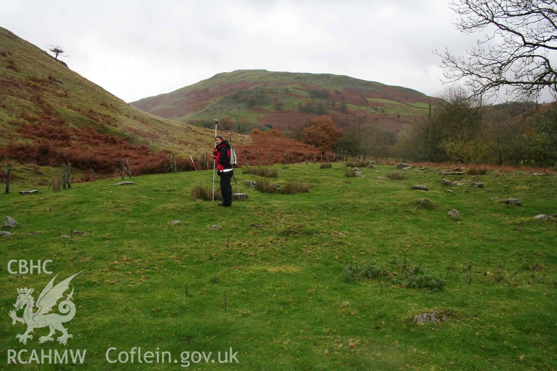 Surveying the earthwork remains of a structure of the Cwm Du settlement from the west