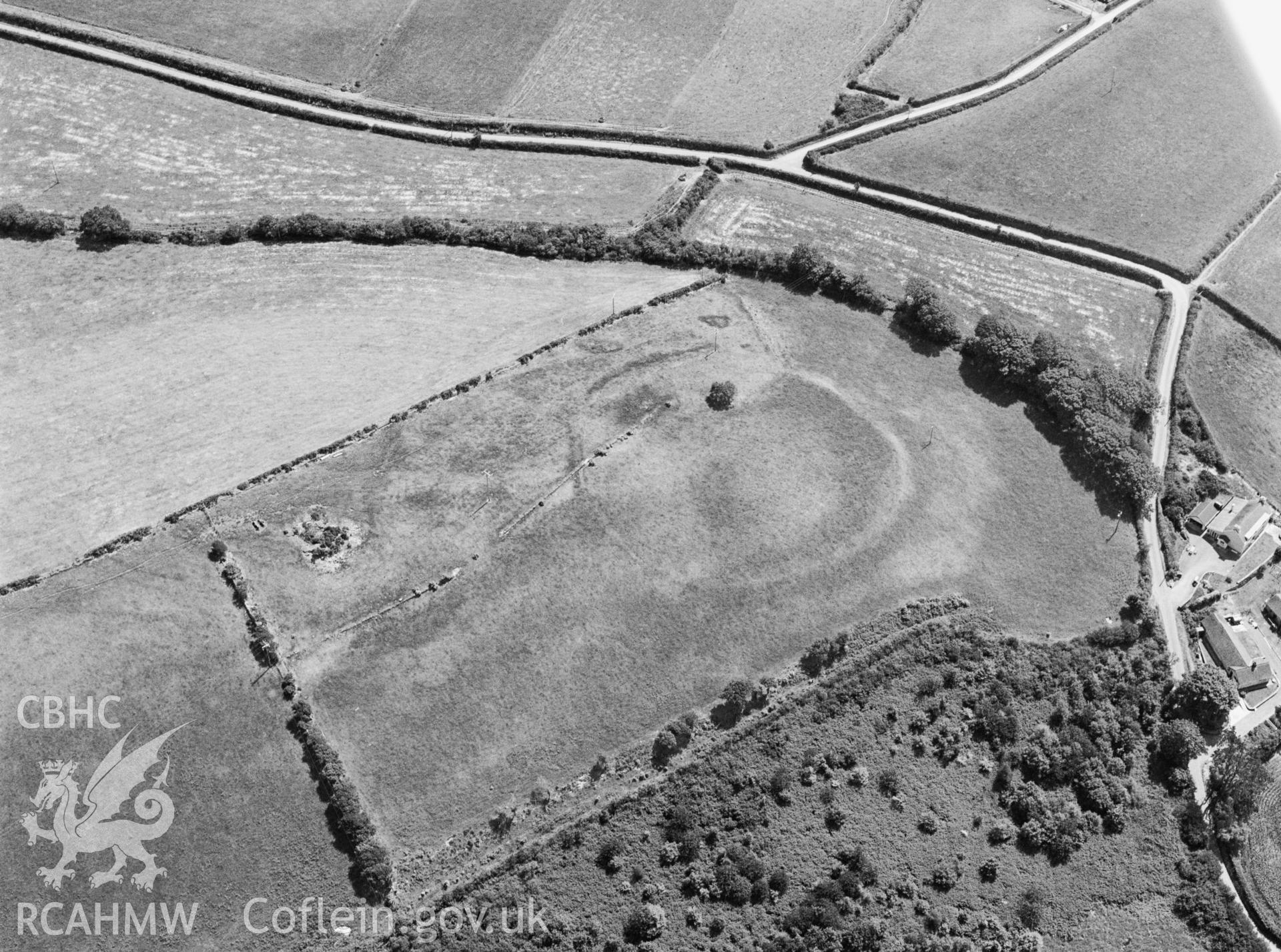 RCAHMW black and white oblique aerial photograph of Troed y Rhiw, defended enclosure, with parchmarks. Taken by Toby Driver on 14/07/2003