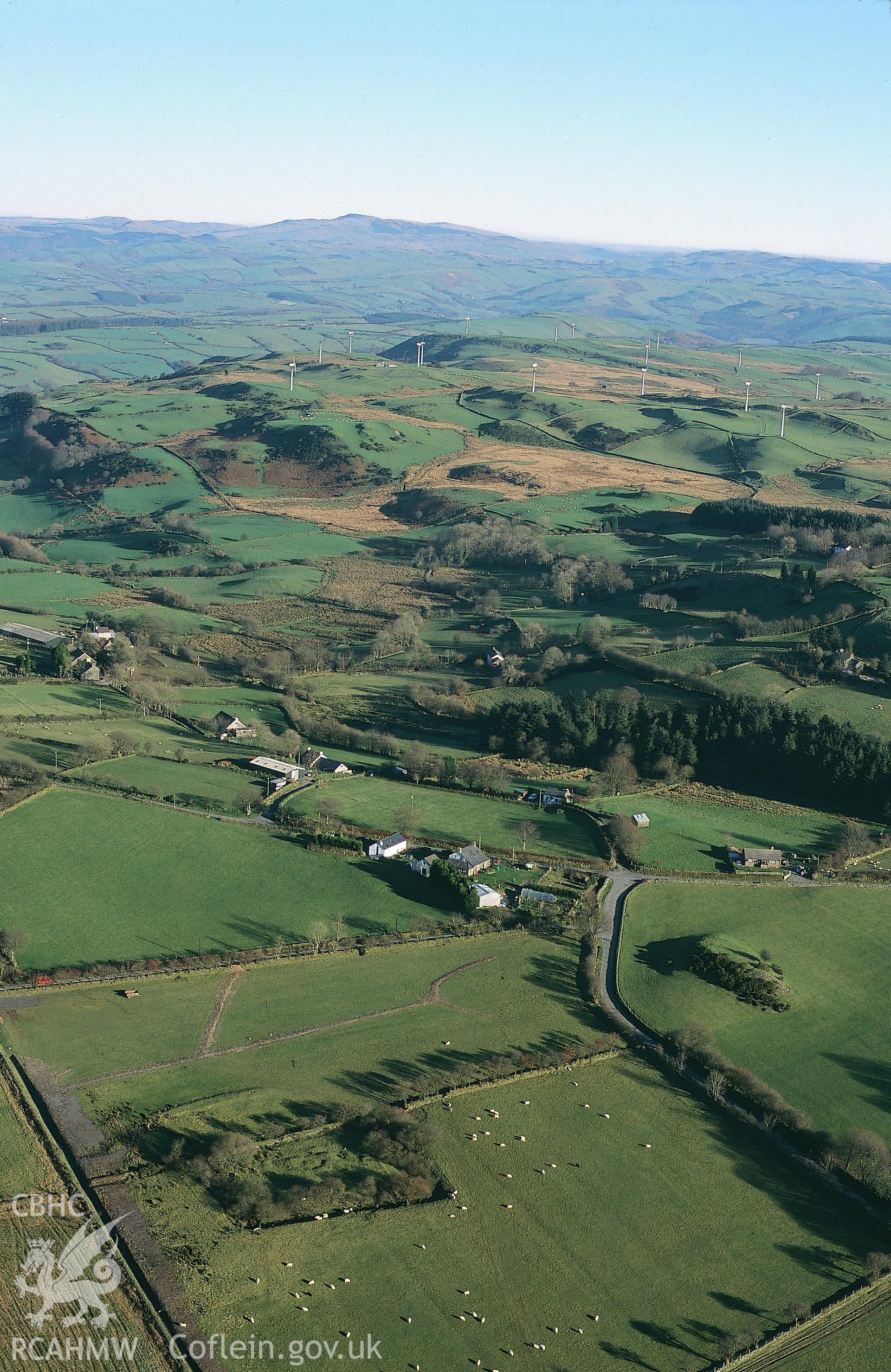 Slide of RCAHMW colour oblique aerial photograph of Trefenter moat, with view of nearby windfarm, taken by T.G. Driver, 2001.