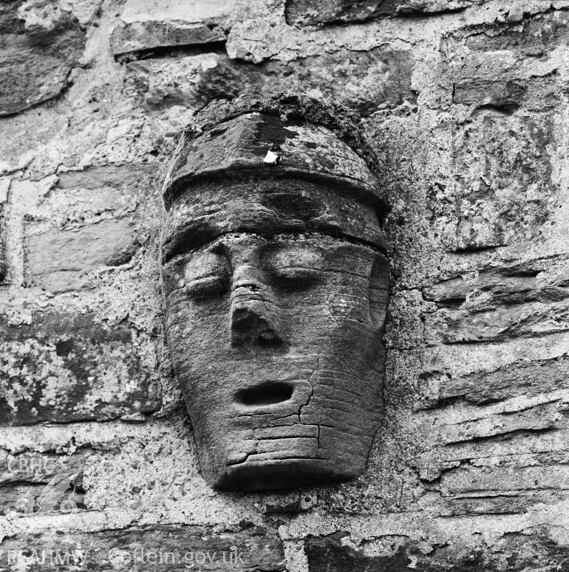 Digitised copy of an RCAHMW b/w photograph of a stone head on the exterior wall of Pantycaregl, Bugeildy, Radnor.