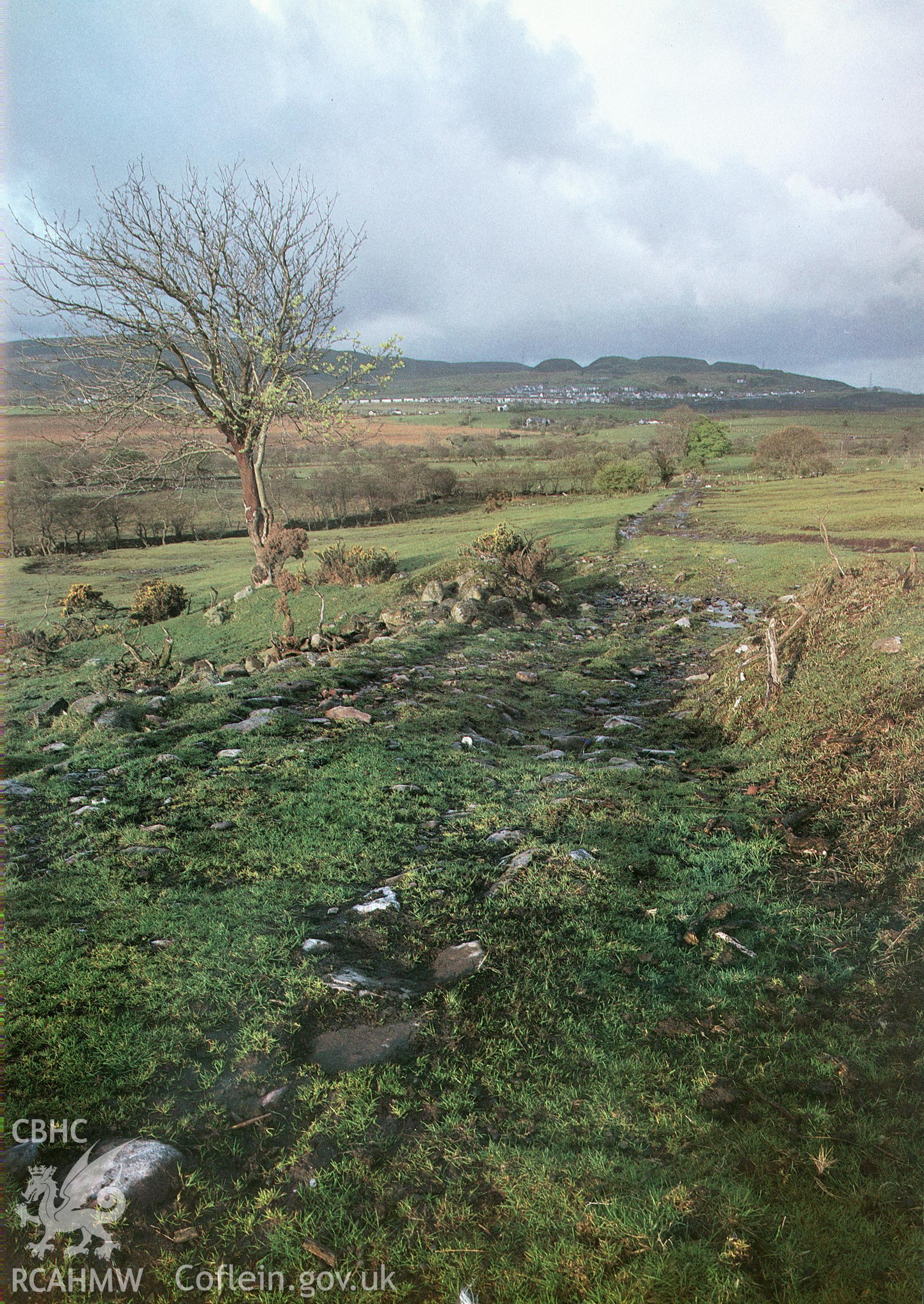 Digitized copy of a colour negative showing a view of Sarn Helen Roman Road looking south-west from SN 8672 1107, as published in RCAHMW inventory volume Brecknock The Prehistoric and Roman Monuments part ii: Hill-forts and Roman Remains 1986 fig 177.