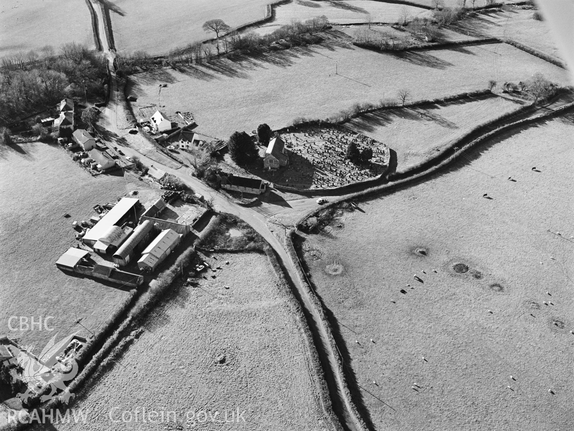 RCAHMW black and white oblique aerial photograph of St. Mary's Church, Llanfair Clydogau, with outer earthwork enclosure. Taken by Toby Driver on 15/11/2002