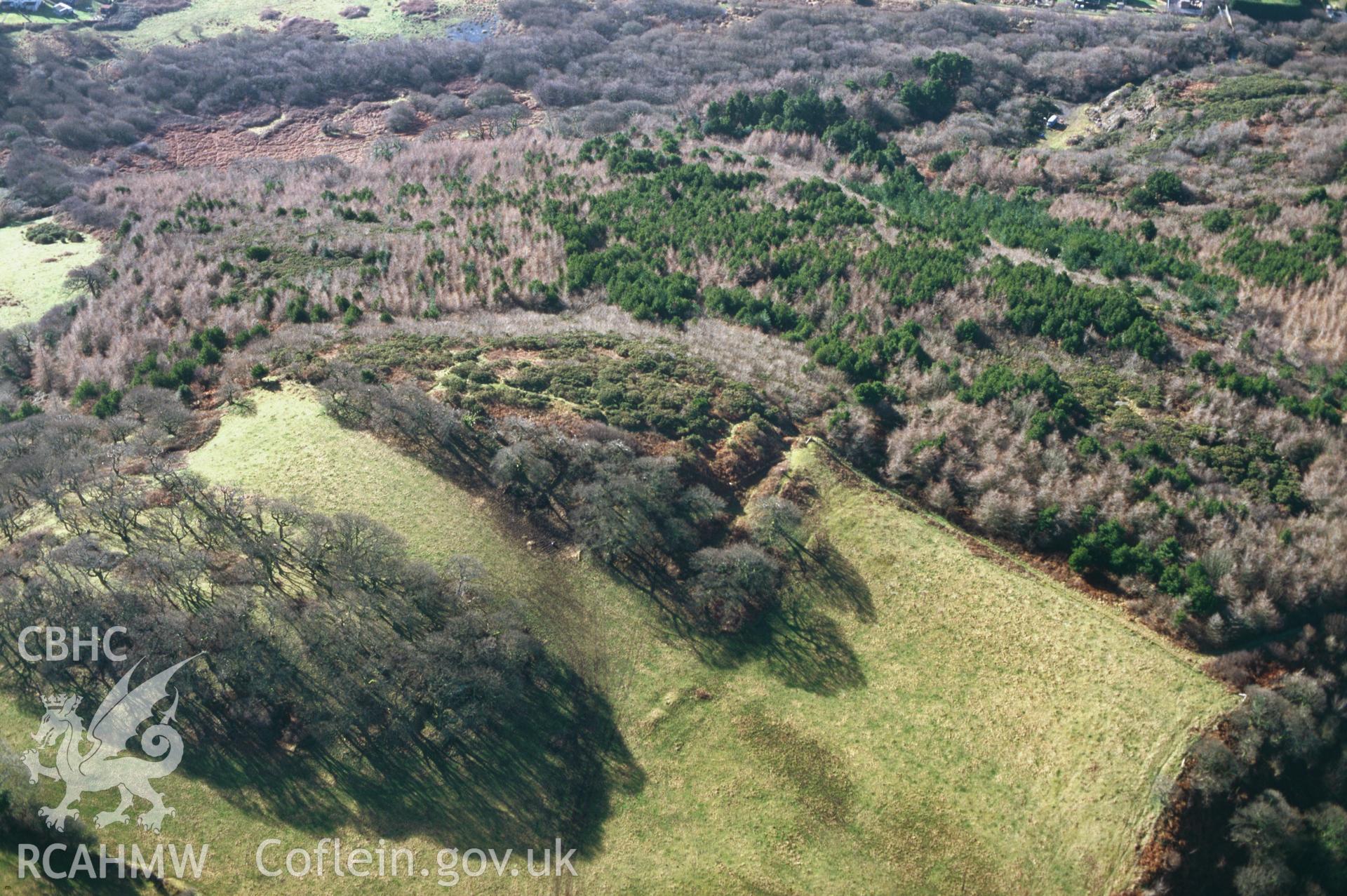 RCAHMW colour slide oblique aerial photograph of Court Wood Enclosure 500m SSW of Pen-llwyn-isaf, Cefn Sidan, taken by C.R.Musson on the 15/02/1997