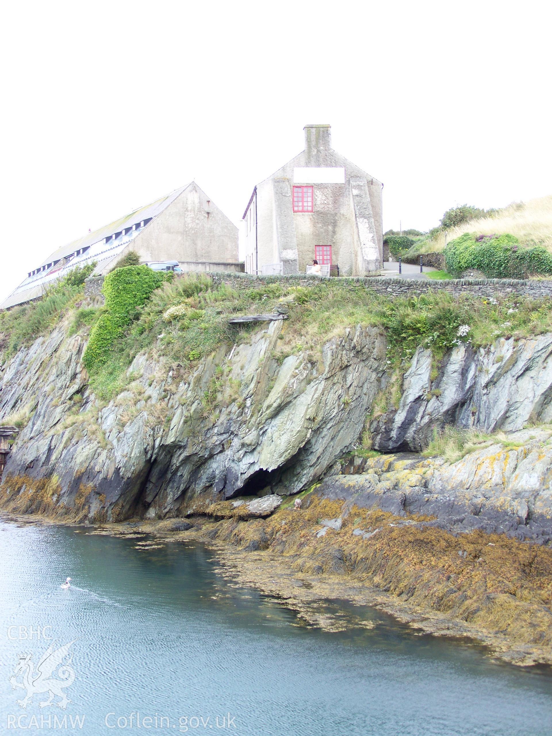 The sail loft viewed from the the western side of the harbour with the base of the yard's former two-seater privvy showing just below the clifftop wall