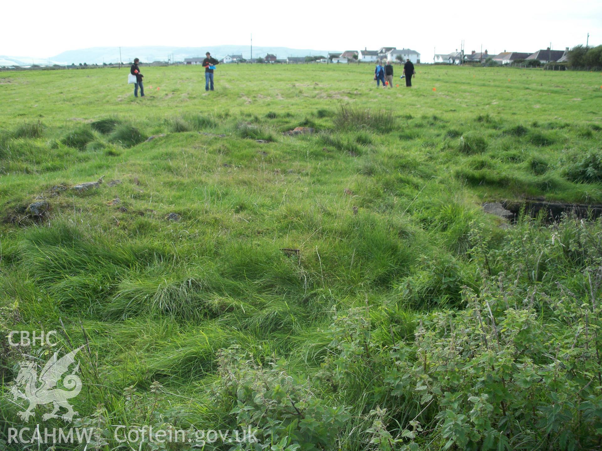 View looking south across field containing other hut platforms being outlined with survey flags by RC staff.