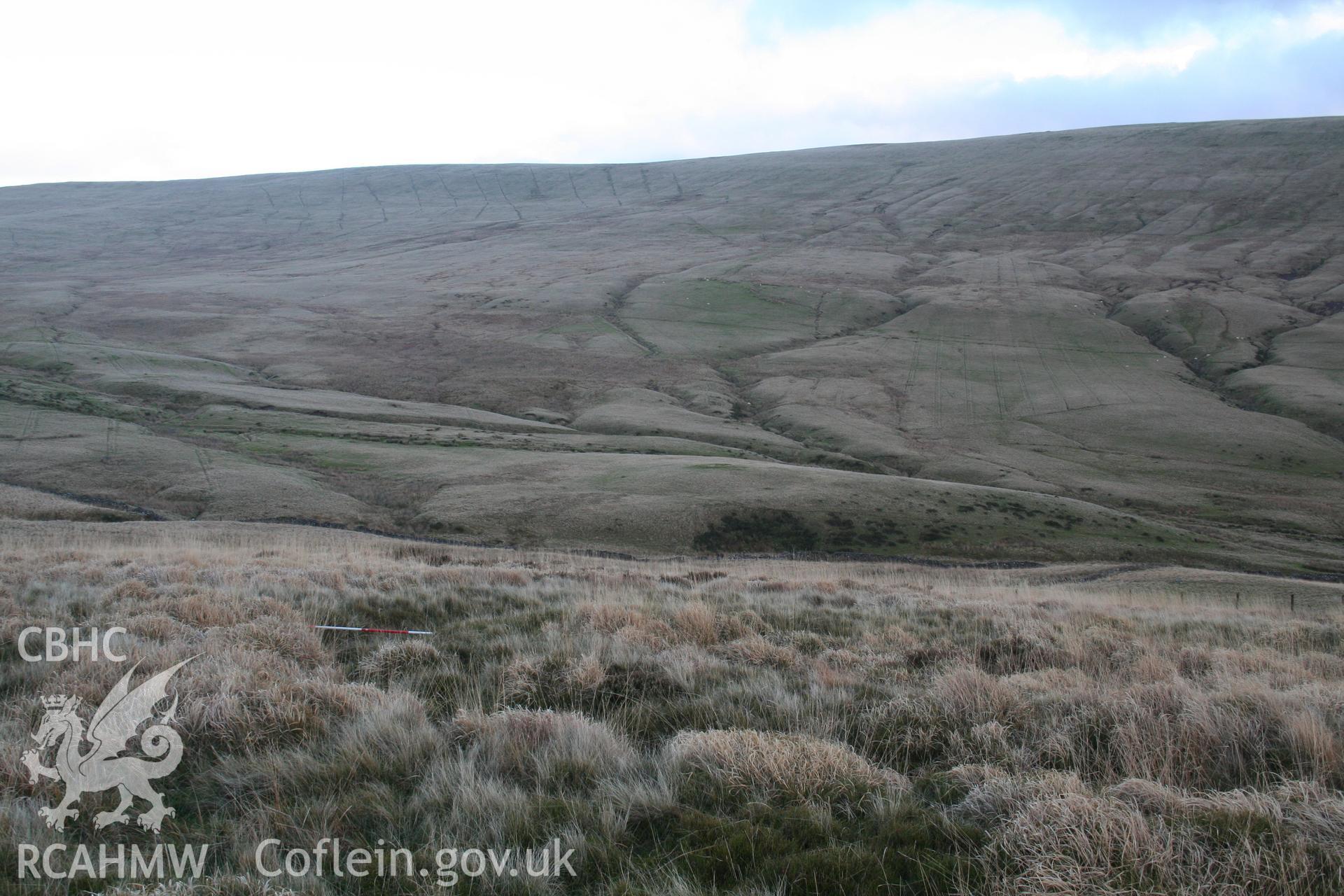 Outer ditch on north side of ringwork, view looking east; 2m scale across ditch; cairn NPRN 84539 in middle distance.