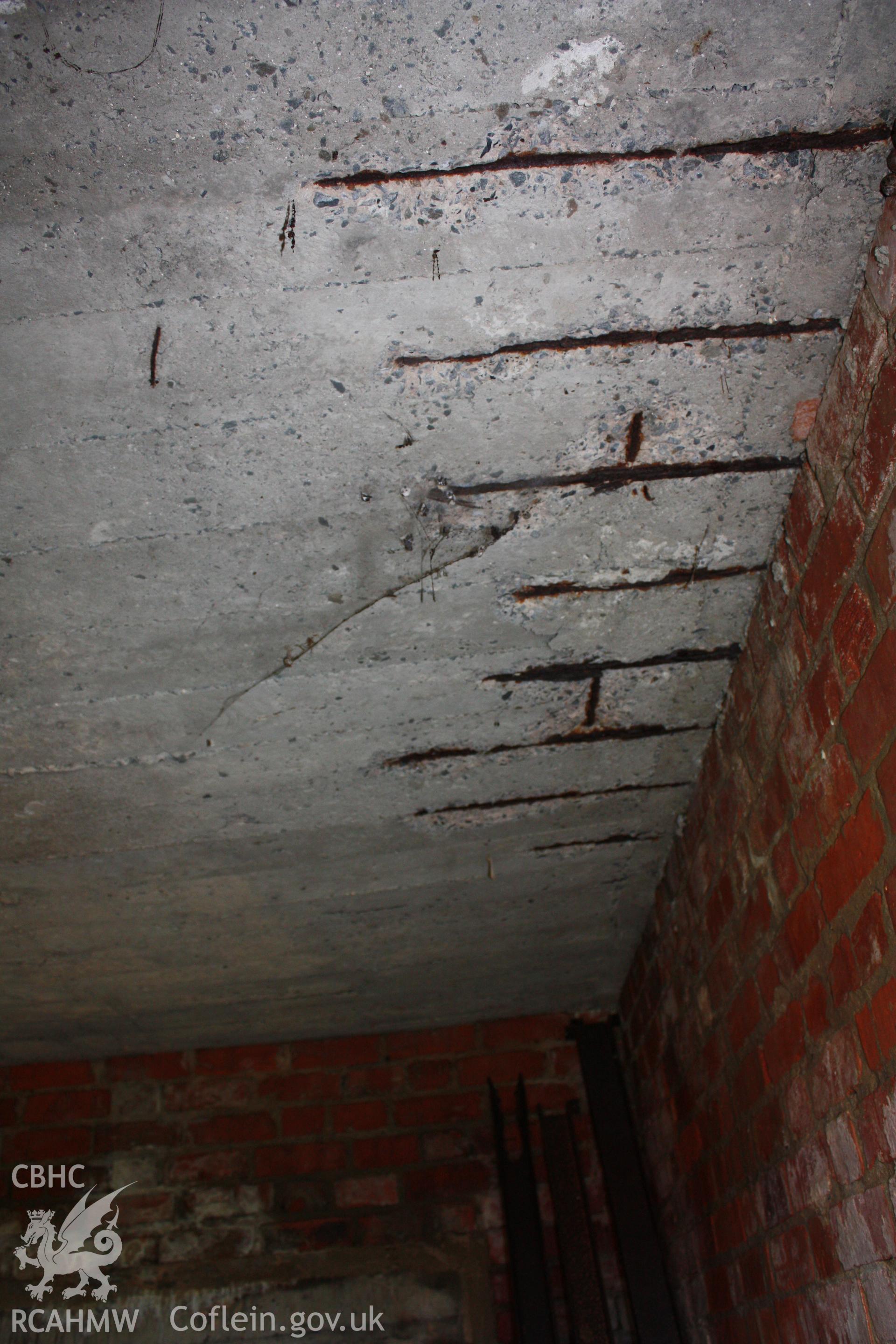 Metal reinforcing visible in underside of concrete roof in southern bay