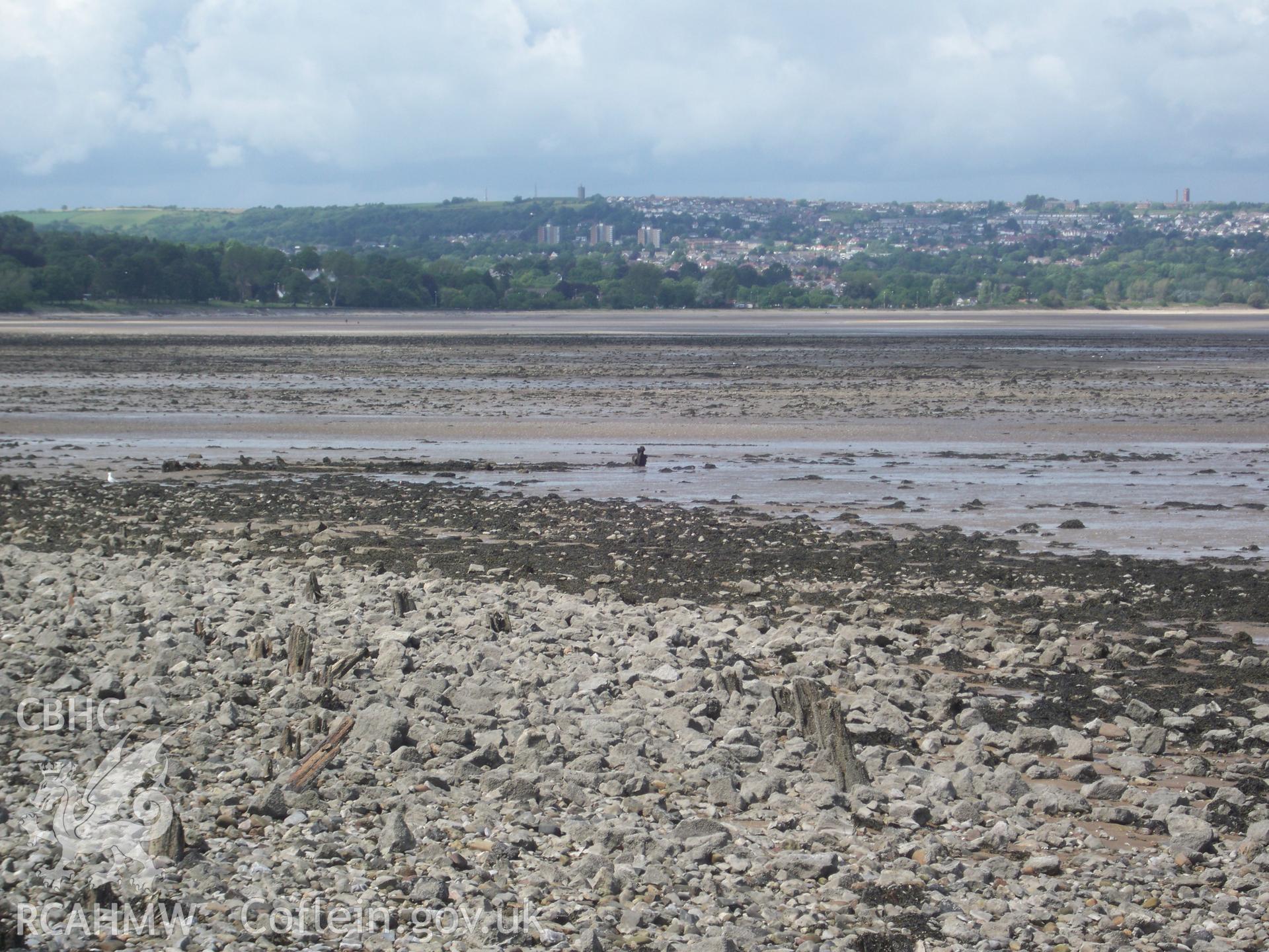 Wreck looking north east from slipway. In foreground, remains of curved breakwater showing as parallel lines of posts.