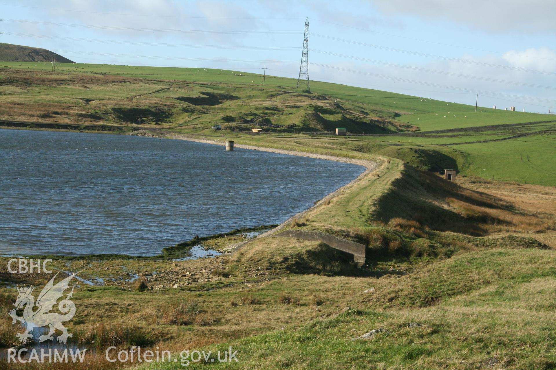 Digital image of Rhaslas Pond and the surrounding area: View  of the north dam, looking west, showing the overspill channel, valve house, and straining tower.