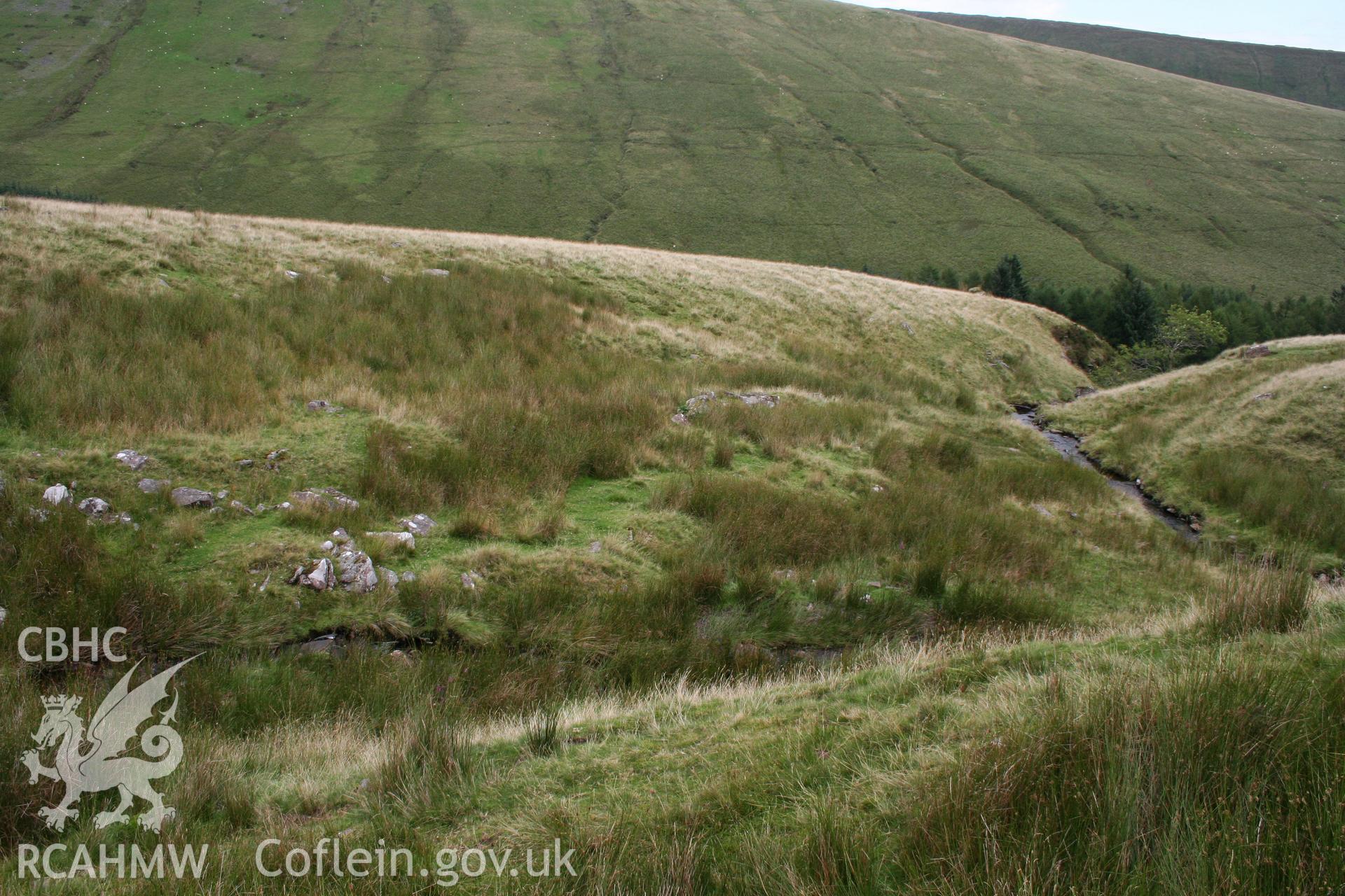 View of stone pile, possibly a former structure, from the west.