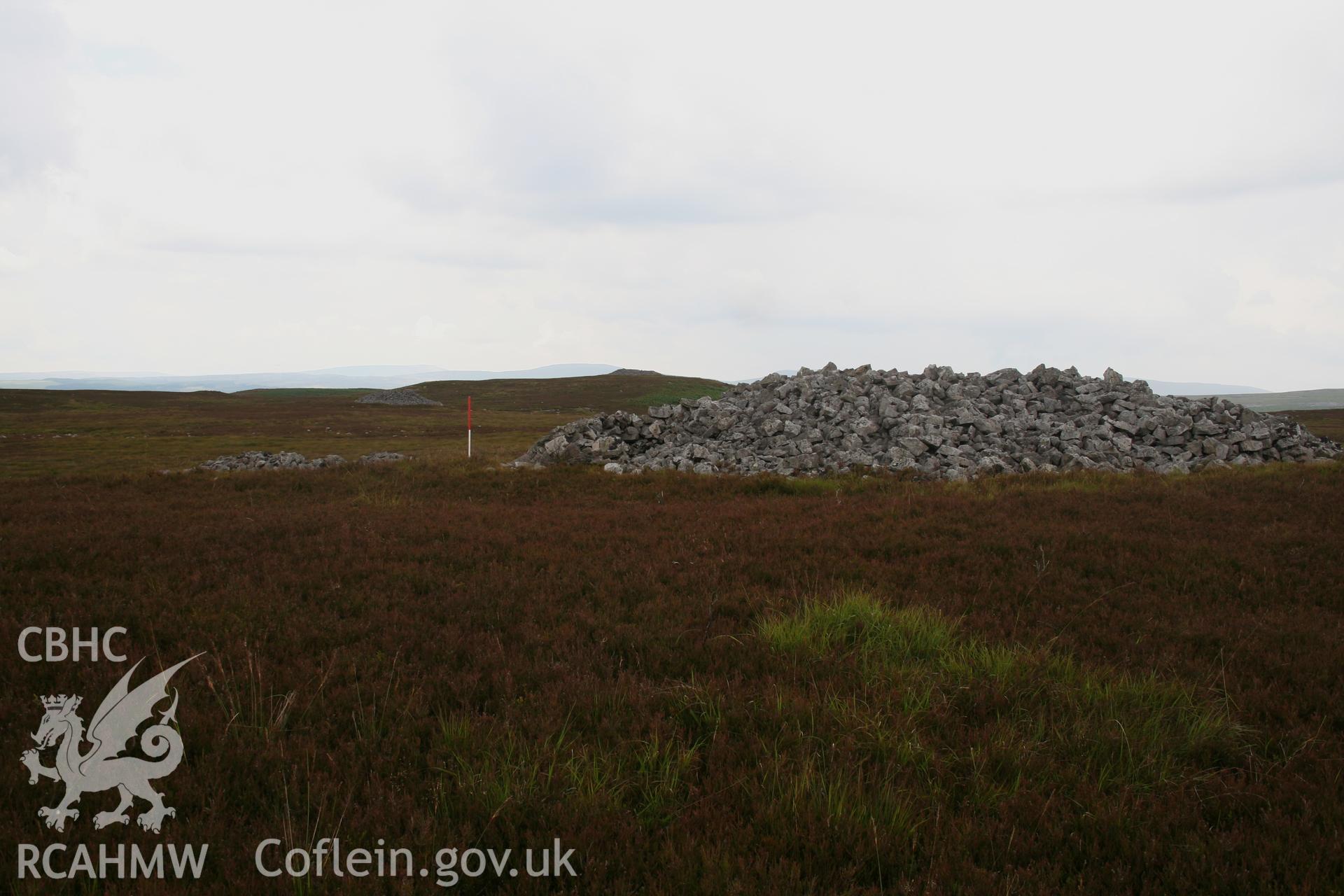 View of cairn from the south-east, 1m scale; note other cemetery mounds in the background.