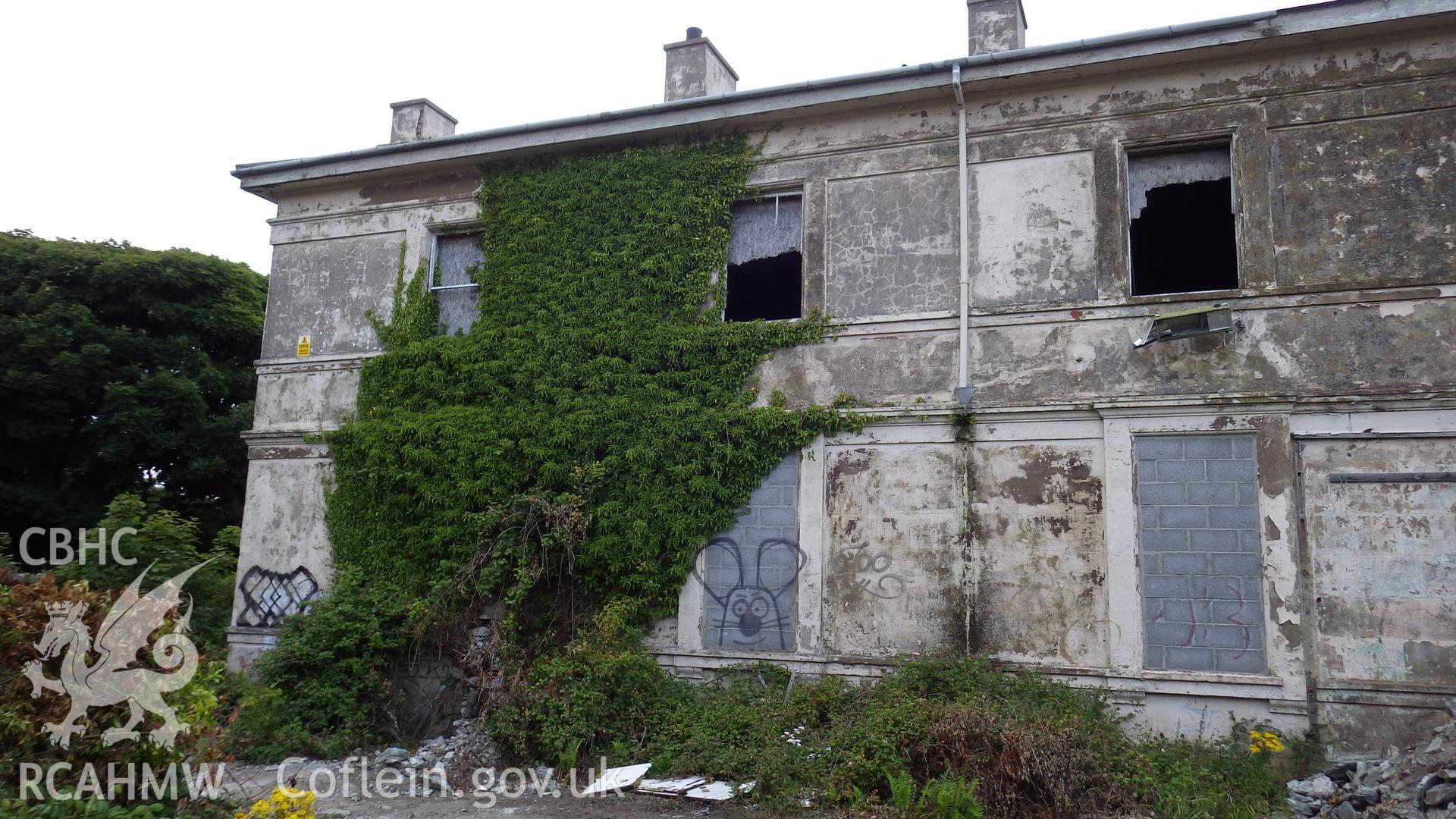 Southern wing viewed from southwest showing windows frames paritally removed on top storey and internal boarding