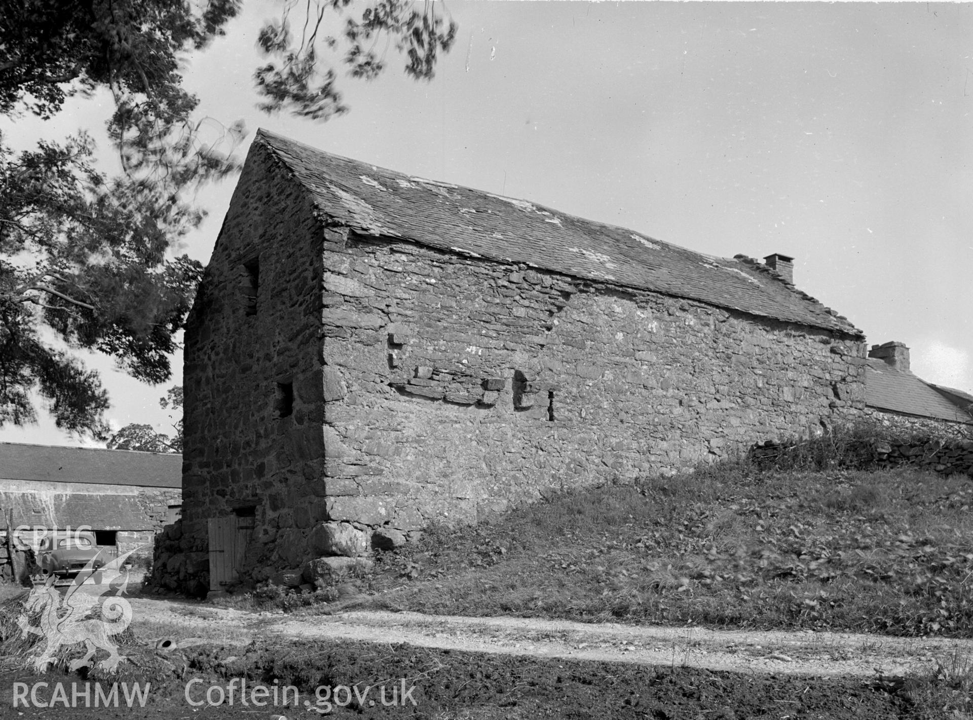 A rectangular stone barn with a slate pitched roof. No windows.