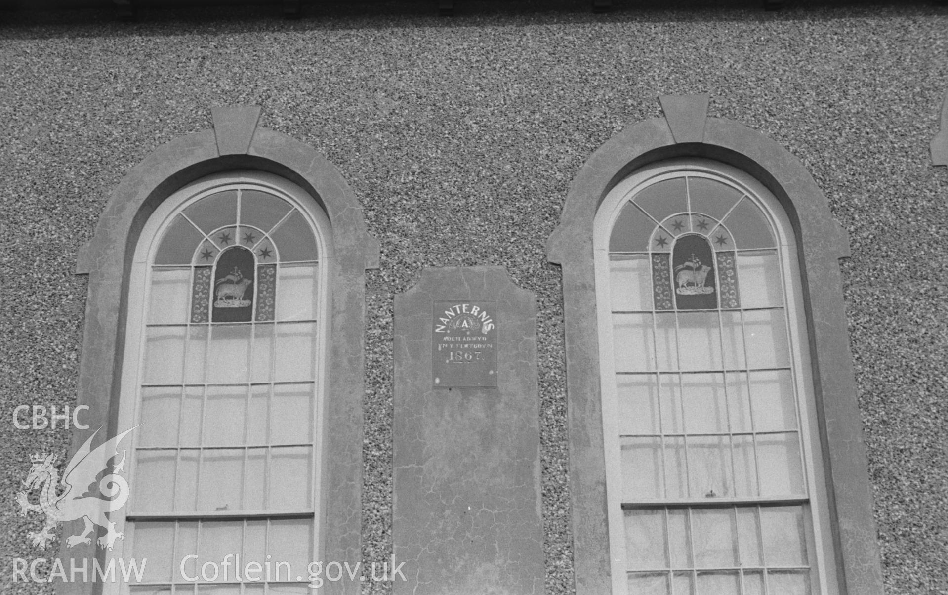 Black and White photograph showing Nanternis Chapel exterior. Two windows with stained glass 'Agnus Dei' on the north western front of the chapel (1867). Photographed by Arthur Chater in April 1963 from Grid Reference SN 372 565, looking south east.