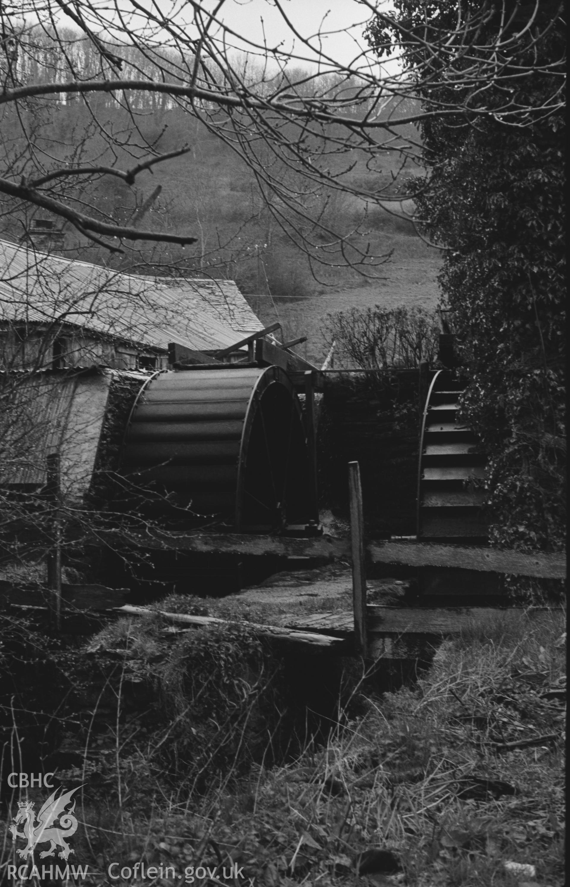 Black and White photograph showing Melin Cwm Ceri. Left hand wheel is overshot, and marked 'Made in Cardigan.' Right hand wheel is undershot. Photographed by Arthur Chater in April 1962 from Grid Reference SN 300 423, looking north.