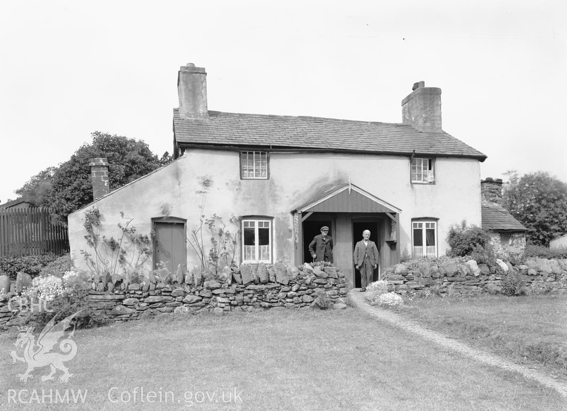 View of the main elevation of the two cottages with two male figures to the fore.