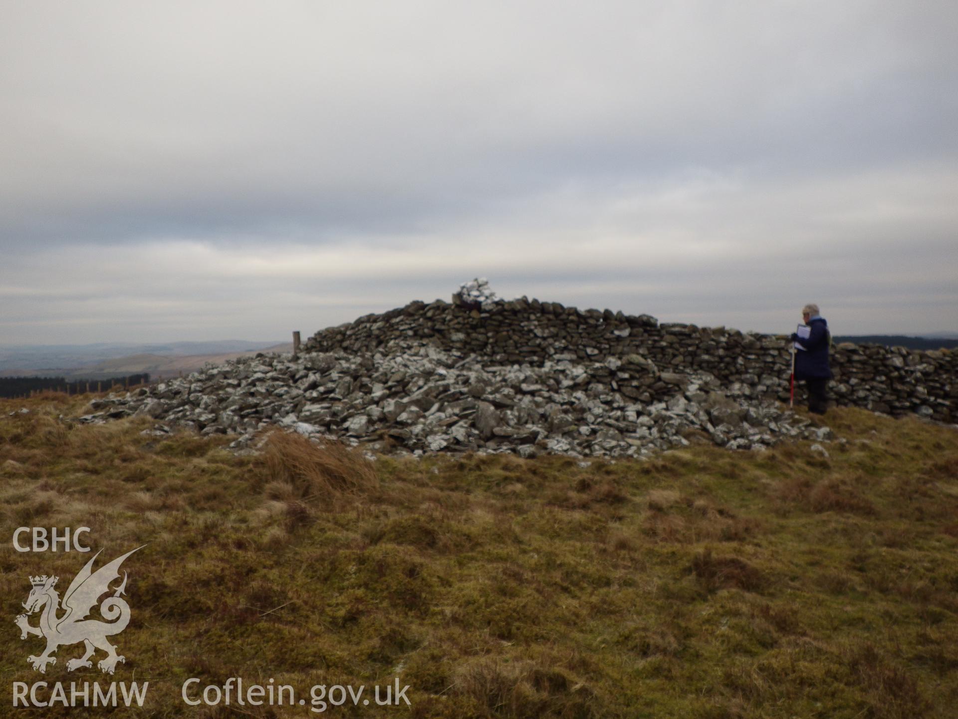 The cairn on Bryn Rhudd with boundary wall running across it, looking north northeast.