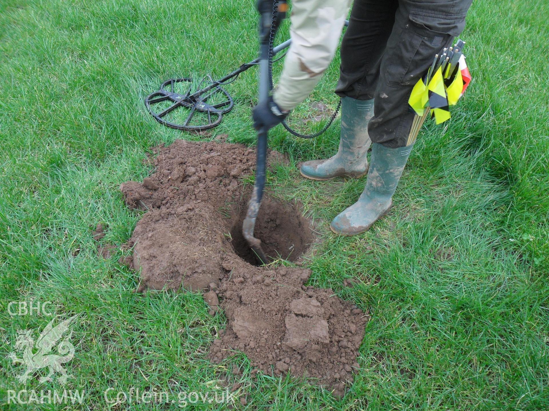 Digital colour photograph of small excavation at Maes Gwenllian battlefield. From report no. 1050 - Maes Gwenllian battlefield, part of the Welsh Battlefield Metal Detector Survey, carried out by Archaeology Wales.