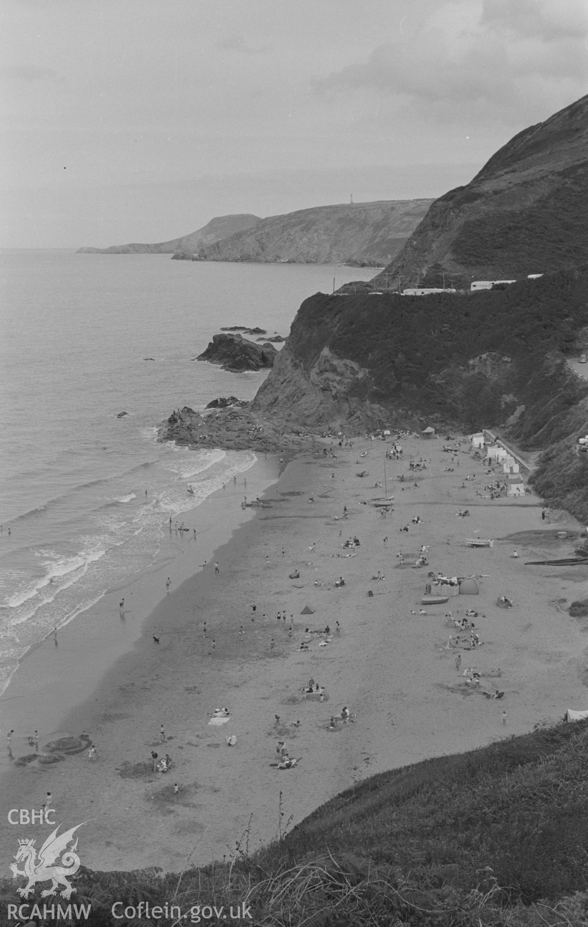 Digital copy of a black and white negative showing view across Tresaith beach and Carregyddafad to Carreg-y-Newydd, Carreg-y-T? and Ynys Llochtyn. Photographed in August 1963 by Arthur O. Chater from Grid Reference SN 2761 5148, looking east north east.