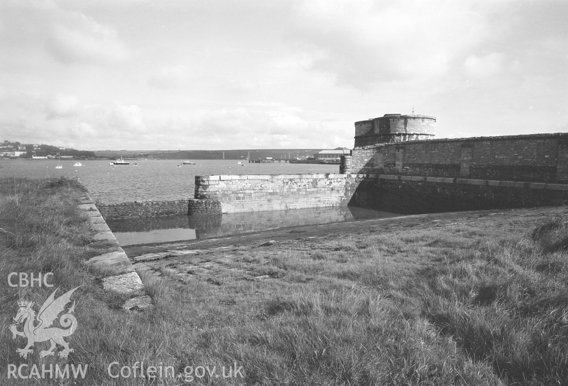 Digital copy of a black and white negative showing Old Royal Dockyard Pembroke - from top of boat slip slope looking NE, inside corner of Dockyard Wall to right & NE Martello Tower taken by RCAHMW