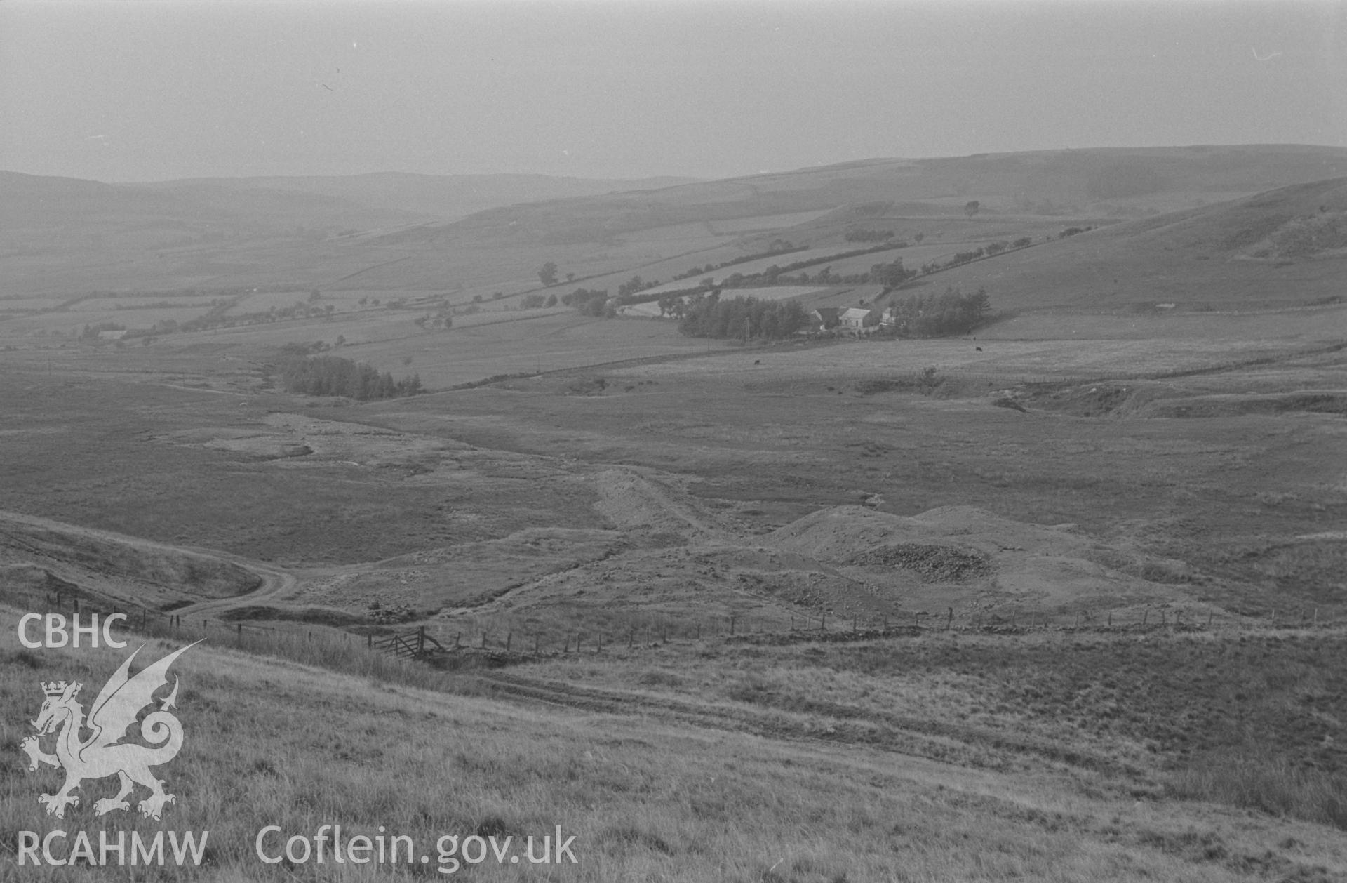 Digital copy of a black and white negative showing old mine workings of Lisburne south mine; Llwyn-y-M?n in trees on right. Photographed by Arthur O. Chater in August 1966 looking north west from Grid Reference SN 747 686.