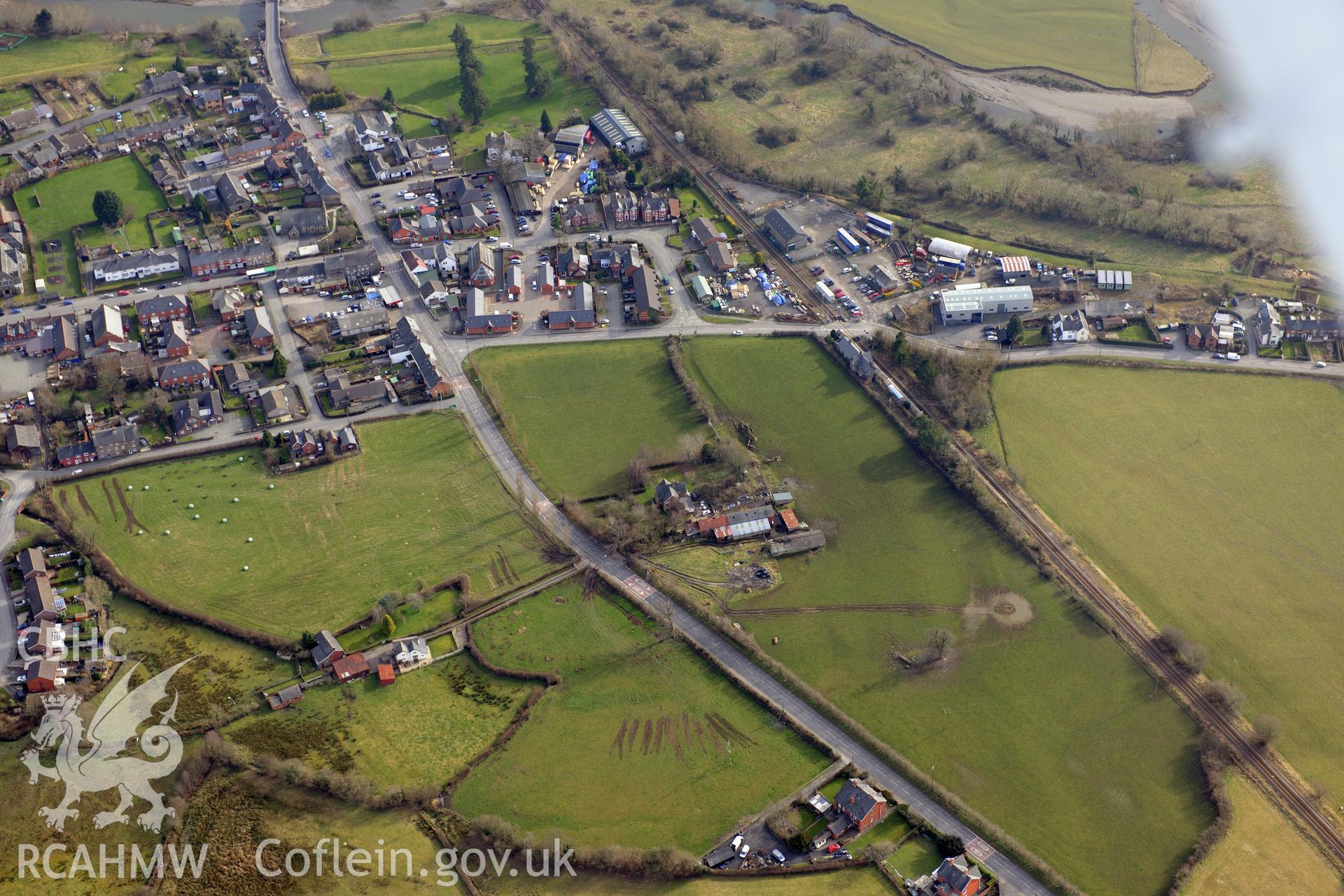 Caersws Roman military settlement and the modern village of Caersws. Oblique aerial photograph taken during the Royal Commission?s programme of archaeological aerial reconnaissance by Toby Driver on 28th February 2013.