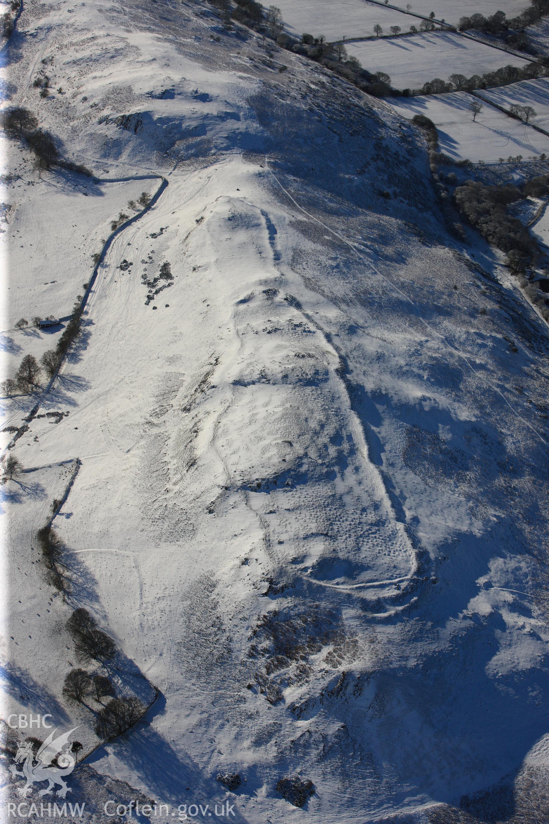 Castle Bank hillfort under snow, north east of Builth Wells. Oblique aerial photograph taken during the Royal Commission?s programme of archaeological aerial reconnaissance by Toby Driver on 15th January 2013.