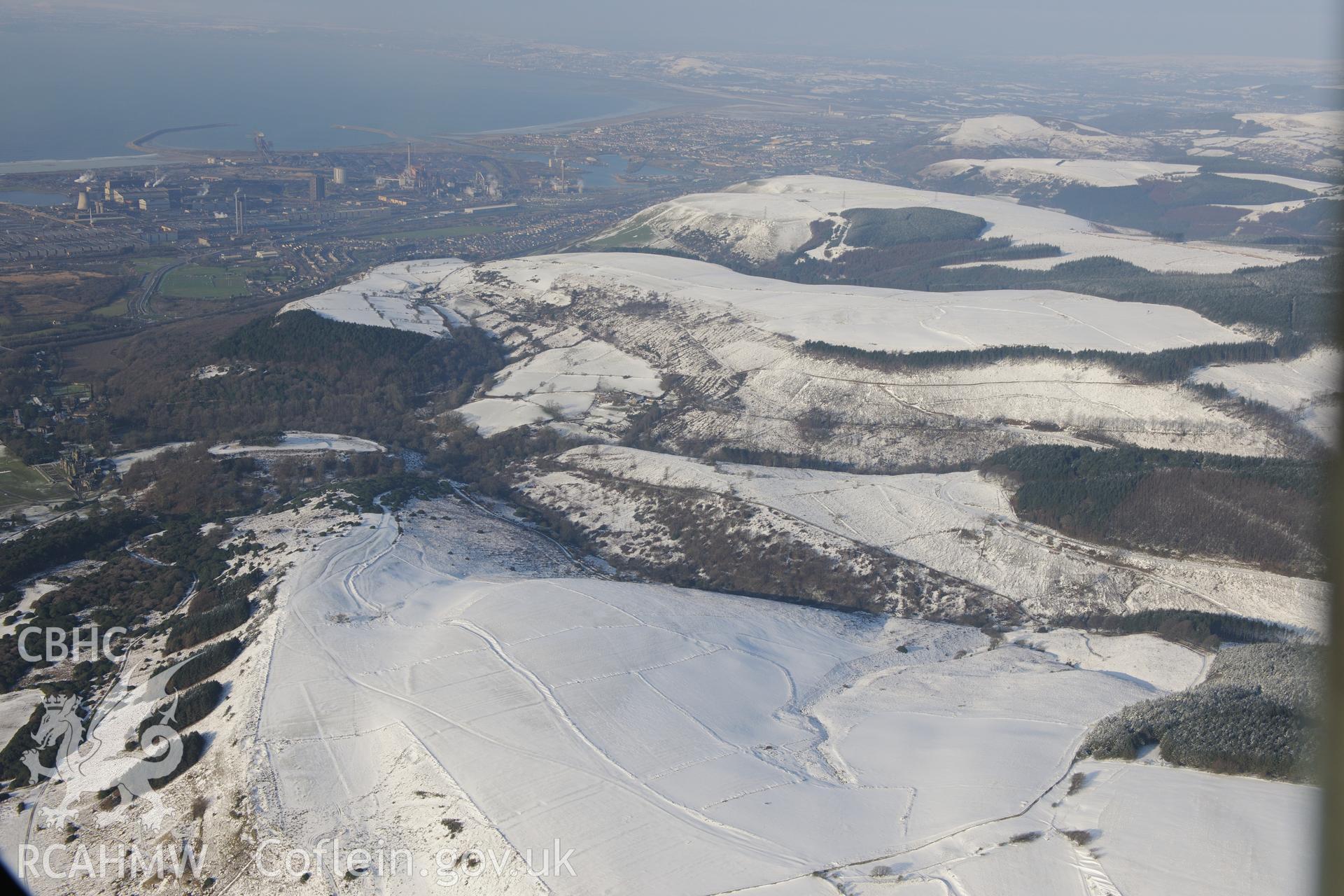 Deserted rural settlement earthworks, with Margam Deer Park and then the Margam Steel Works beyond, Margam, Port Talbot. Oblique aerial photograph taken during the Royal Commission?s programme of archaeological aerial reconnaissance by Toby Driver on 24th January 2013.