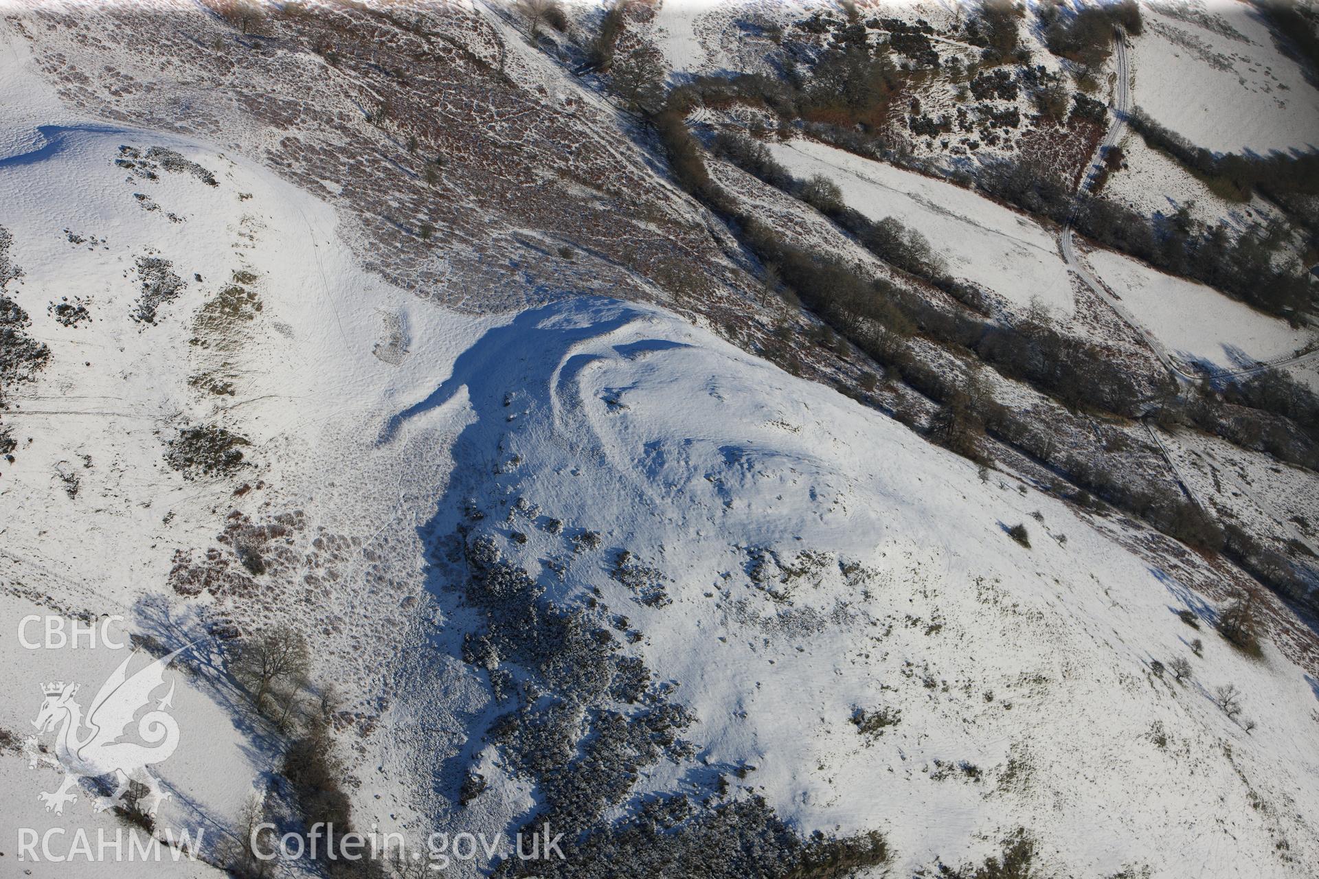 Caer Einon hillfort and three hut platforms, north east of Builth Wells. Oblique aerial photograph taken during the Royal Commission?s programme of archaeological aerial reconnaissance by Toby Driver on 15th January 2013.