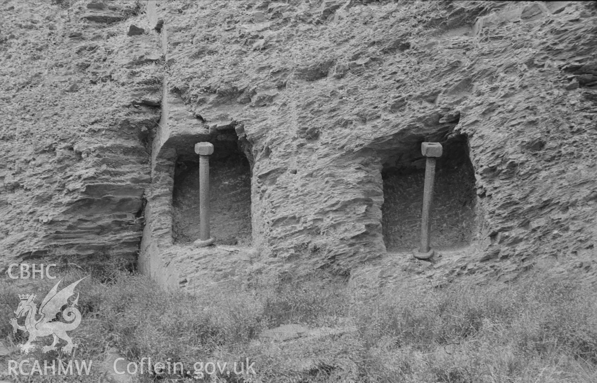 Digital copy of a black and white negative showing iron bars set in cavities in rock at Abbey Consols mine, just west of the ruins of the (?)wheel pit. Photographed by Arthur O. Chater on 25th August 1967, looking north from Grid Reference SN 743 662.