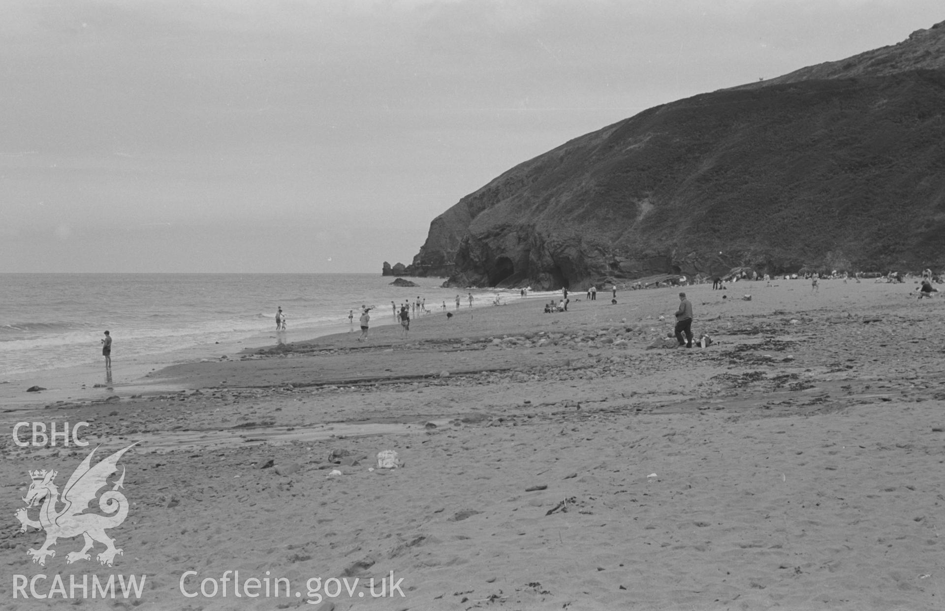 Digital copy of a black and white negative showing beach and holiday makers at Tresaith, Cardigan. Photographed in August 1963 by Arthur O. Chater from Grid Reference SN 2765 5153, looking east north east.