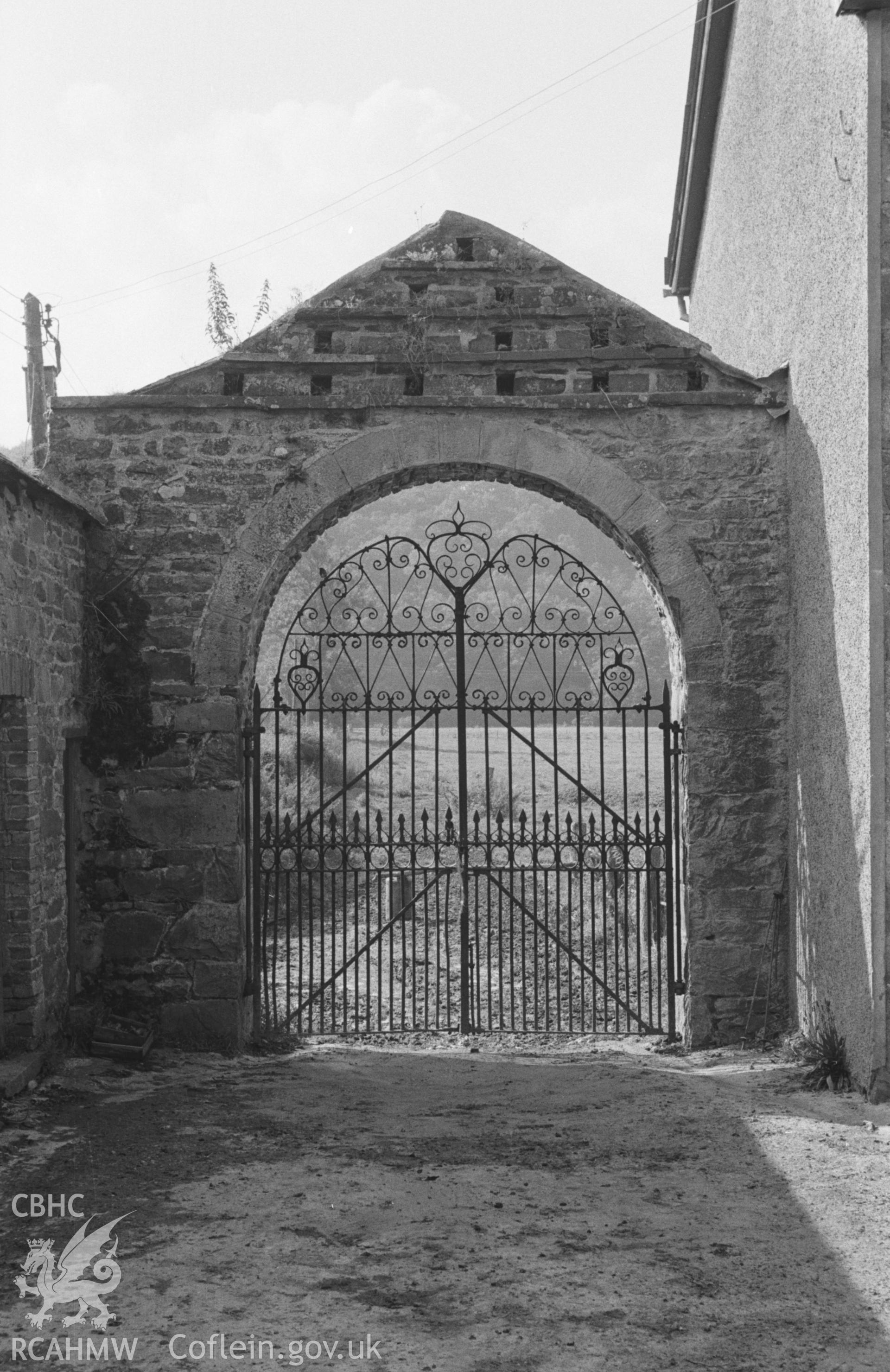 Digital copy of black & white negative showing wrought iron ornate gates at the south east corner of Llanfair farmyard, Llandysul; dovecote above. Photographed by Arthur O. Chater in August 1965 from Grid Reference SN 4331 4093, looking west north west.