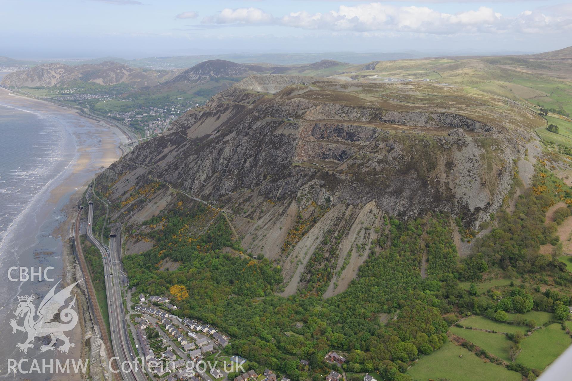 Penmaenmawr quarry, Braich-y-Dinas hillfort and Penyclip road tunnels, Penmaenmawr. Oblique aerial photograph taken during the Royal Commission?s programme of archaeological aerial reconnaissance by Toby Driver on 22nd May 2013.