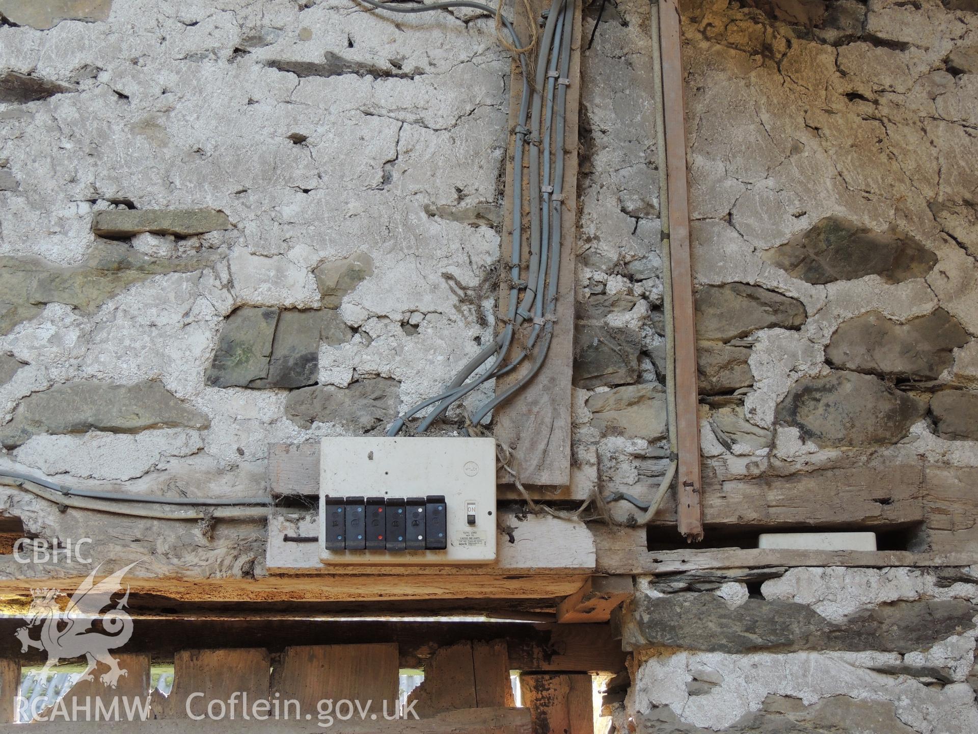 Fuse box above entrance, looking south east. Photograph taken as part of archaeological building survey conducted at Bryn Gwylan Threshing Barn, Llangernyw, Conwy, carried out by Archaeology Wales, 2017-2018. Report no. 1640. Project no. 2578.