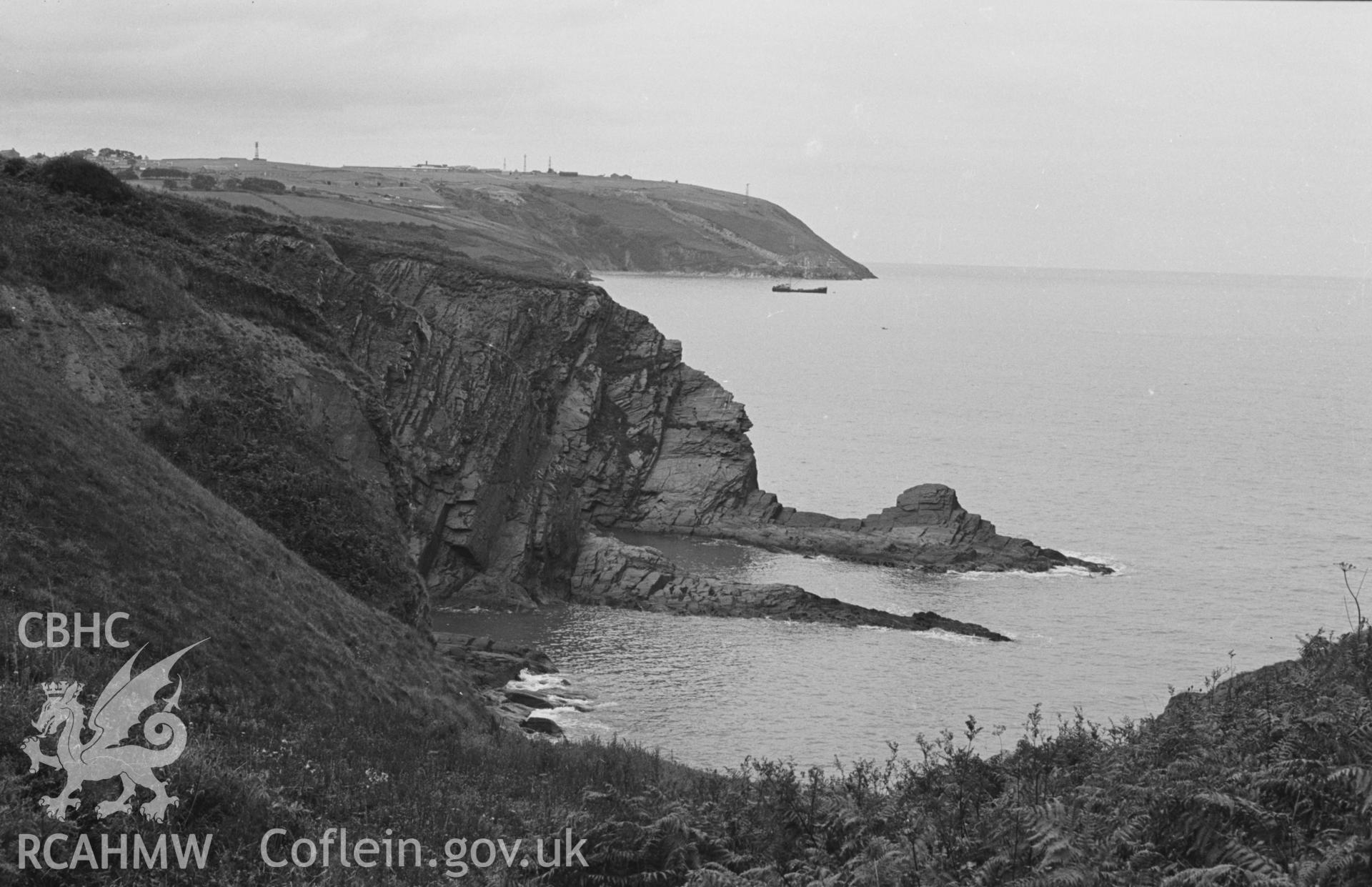 Digital copy of black & white negative showing Traeth Bach-yr-Helyg, with Pencribach in distance, seen from footpath along cliffs 800m west of Tresaith. Photograph by Arthur O. Chater, August 1963, from Grid Reference SN 2714 5147, looking west north west.