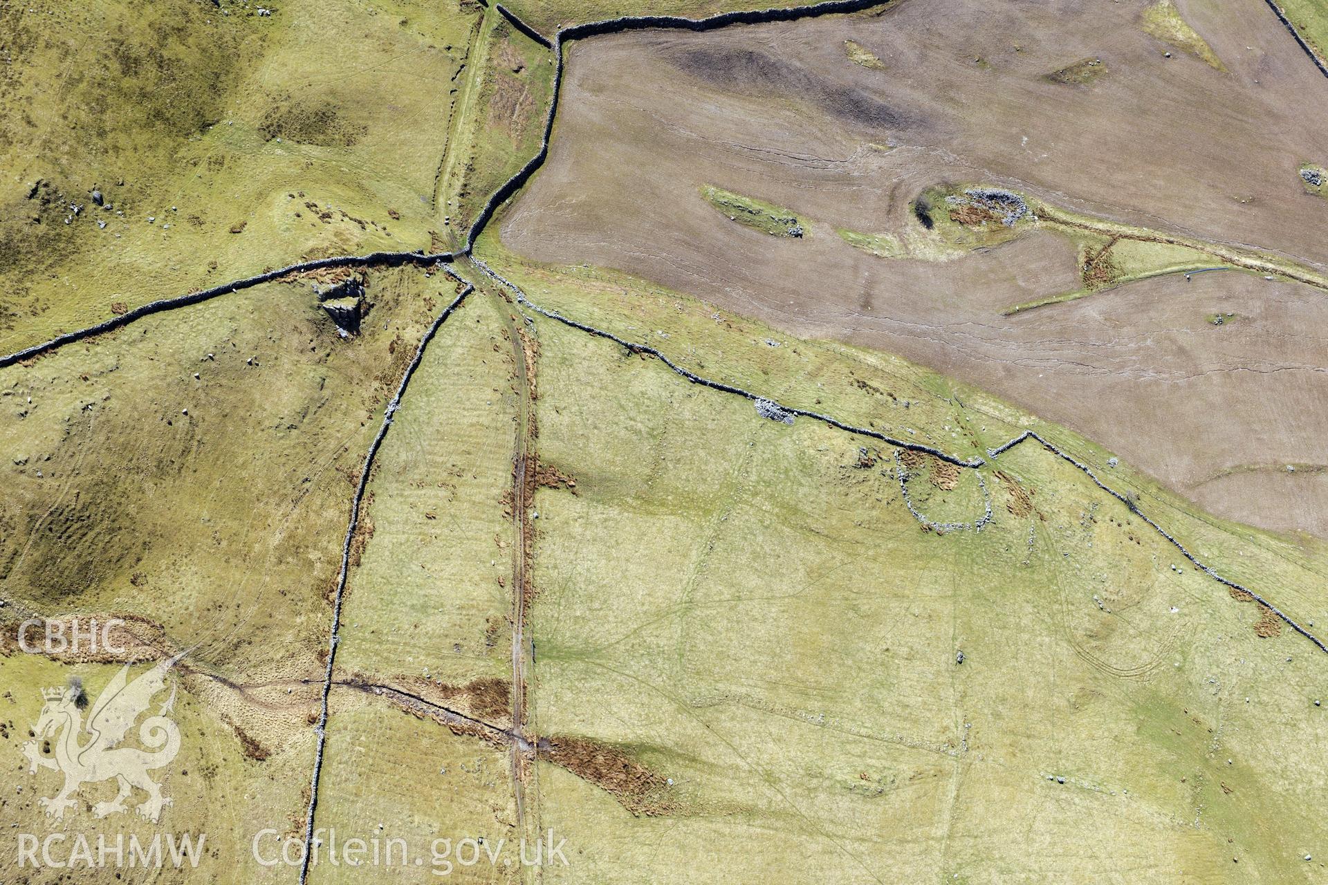 Ffridd Fedw round hut, enclosure, ancient field and kerb cairn, Talsarnau, north east of Harlech. Oblique aerial photograph taken during the Royal Commission?s programme of archaeological aerial reconnaissance by Toby Driver on 1st May 2013.