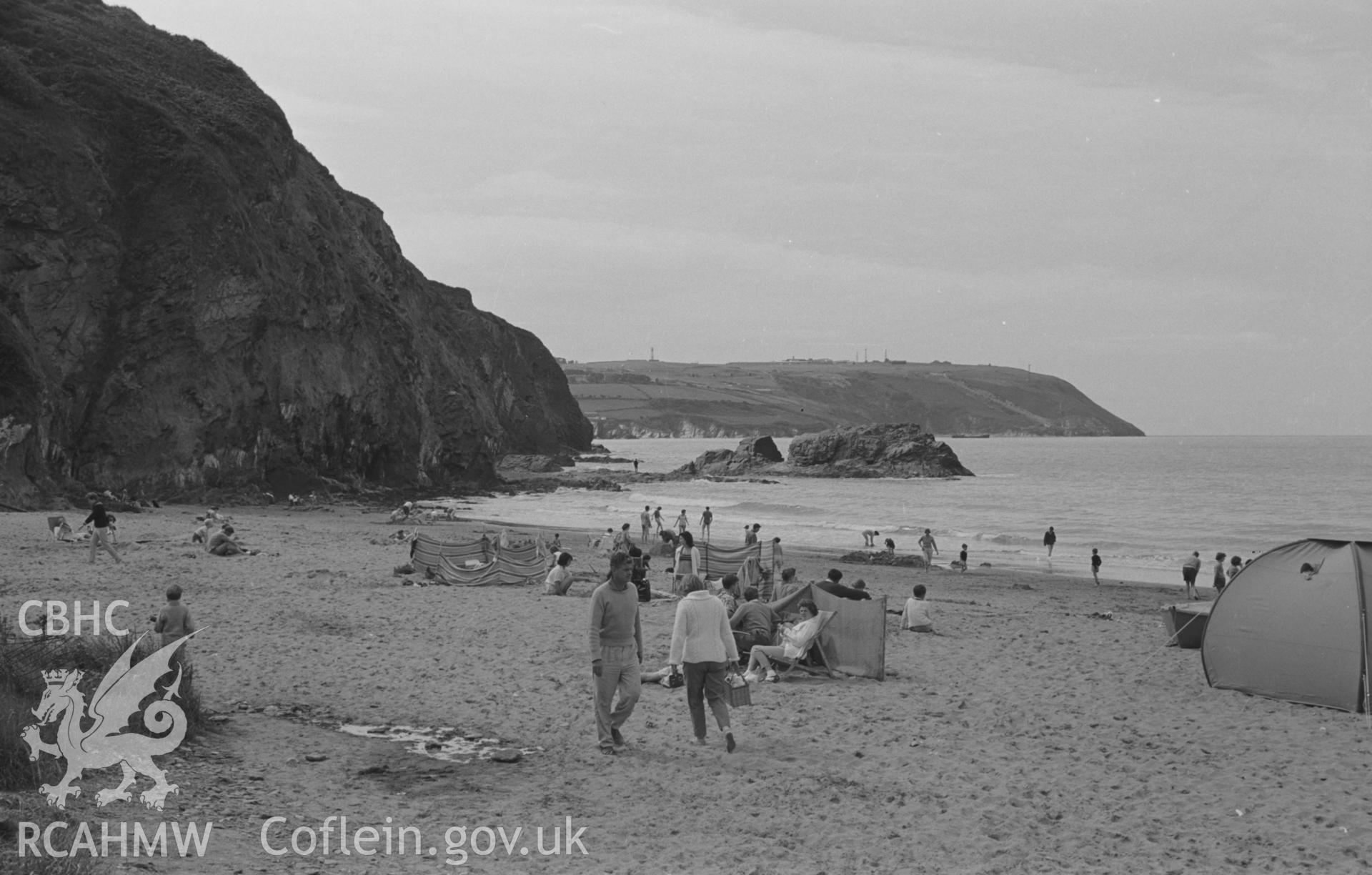 Digital copy of a black and white negative showing view from Tresaith beach with holiday makers to Pencribach, beyond Aberporth. Photographed in August 1963 by Arthur O. Chater from Grid Reference SN 2772 5154, looking west north west.