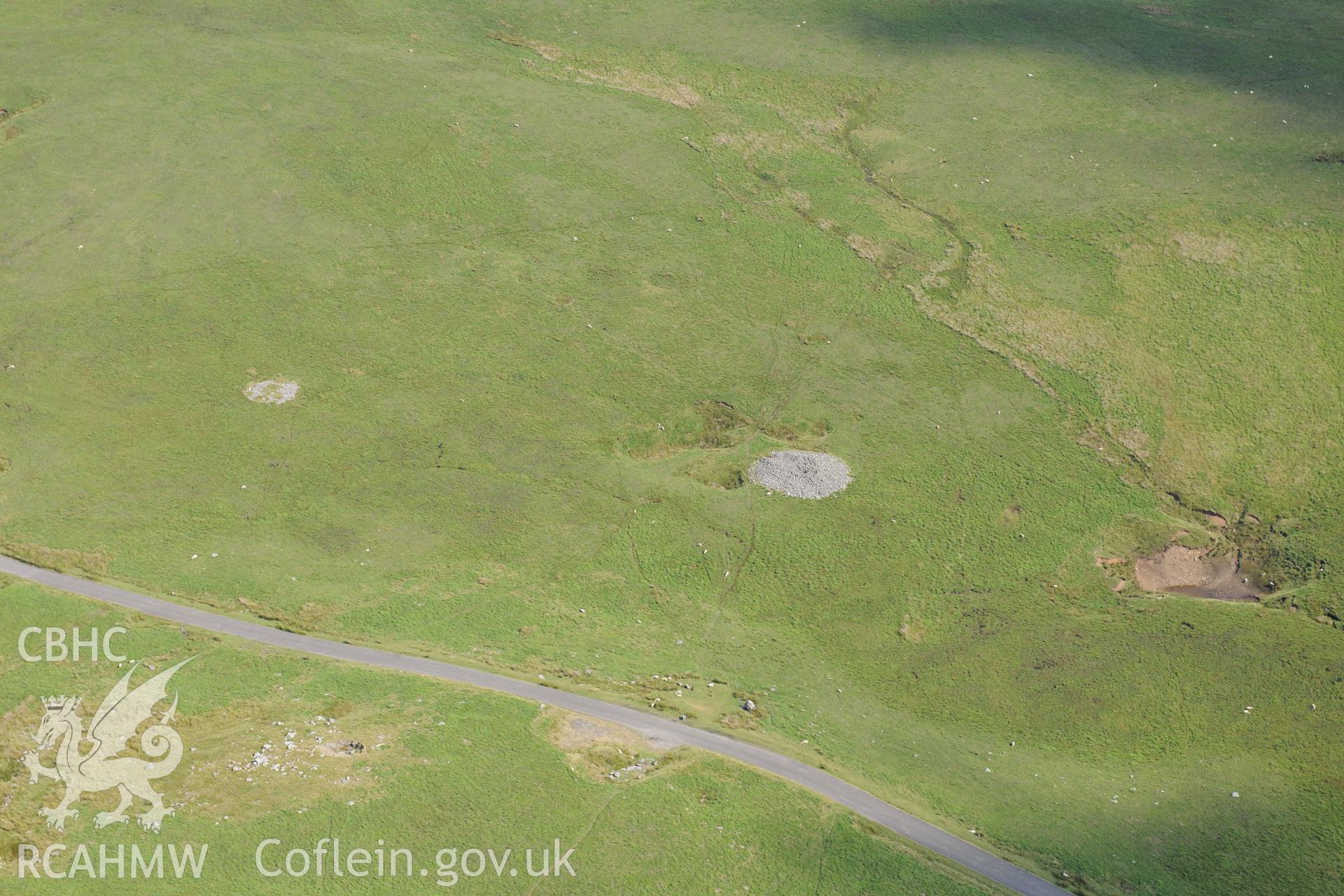 Cairn and cairn ring on northern side of Cefn Sychbant, and Cwm Cadlan quarry, north west of Merthyr Tydfil. Oblique aerial photograph taken during the Royal Commission?s programme of archaeological aerial reconnaissance by Toby Driver on 1st August 2013.