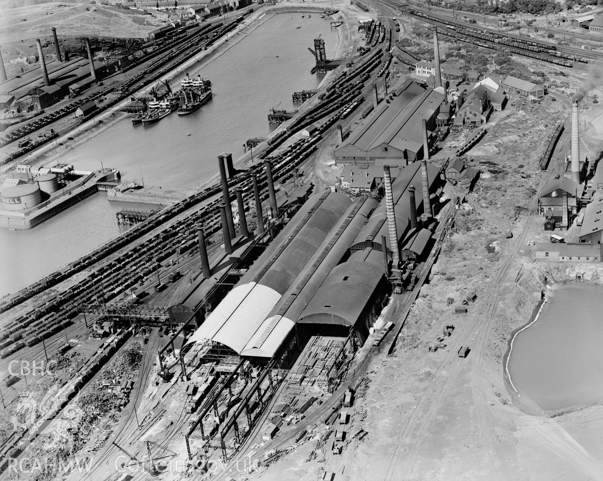 View of Briton Ferry Dock showing Baglan Bay Tinplate Co., Briton Ferry Steel Works, Albion Steelworks and Whitford Works, from the south, oblique aerial view. 5?x4? black and white glass plate negative.