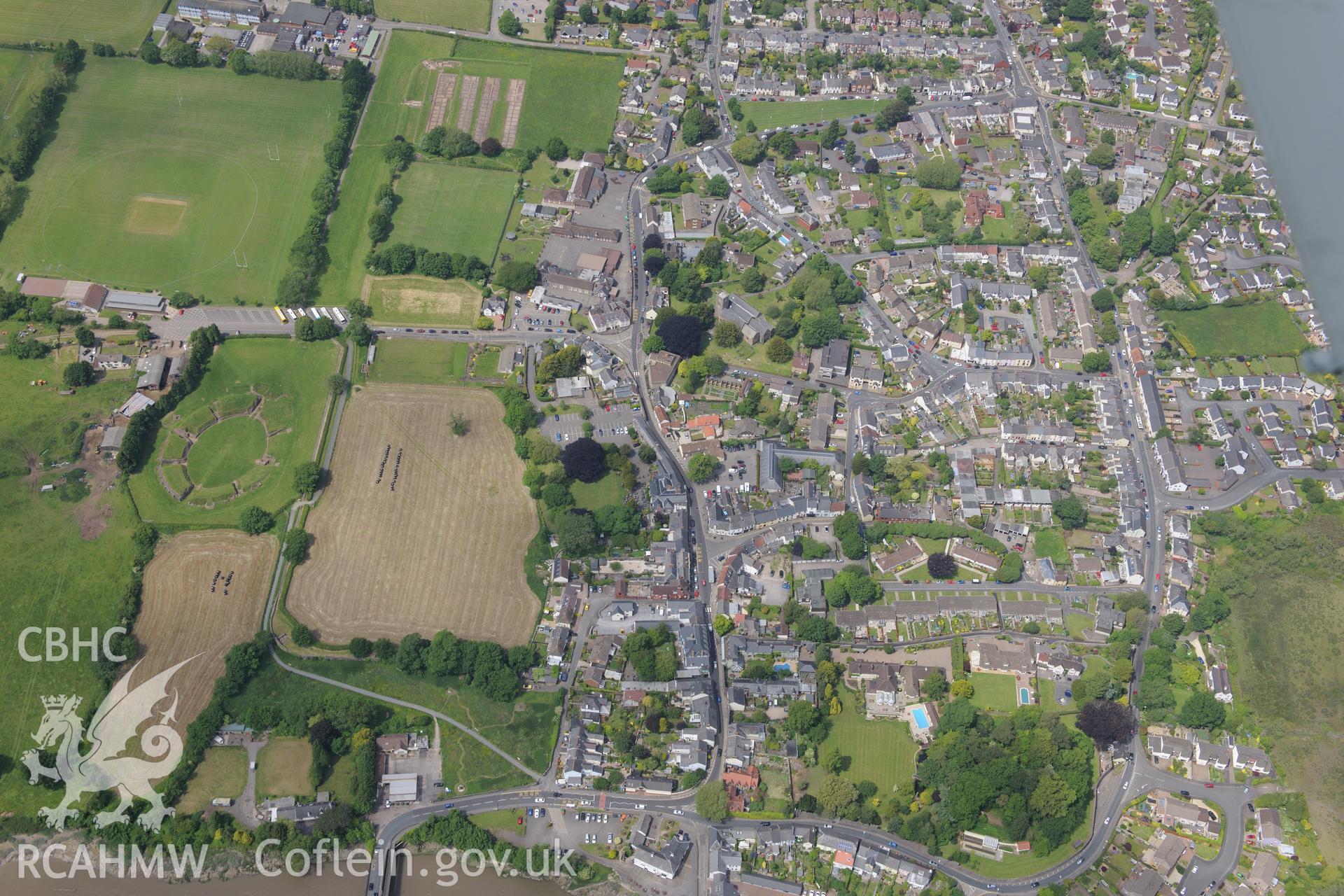 Caerleon town including the Roman barracks; amphitheatre and parade grounds and a modern cricket pavillion. Oblique aerial photograph taken during the Royal Commission's programme of archaeological aerial reconnaissance by Toby Driver on 11th June 2015.