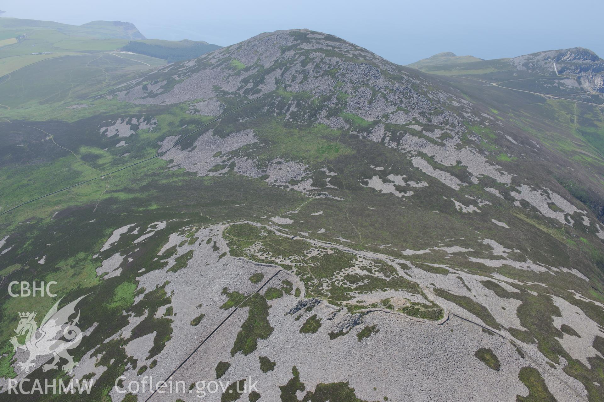 Tre'r Ceiri hillfort with the village of Trefor beyond, on the Lleyn Peninsula. Oblique aerial photograph taken during the Royal Commission?s programme of archaeological aerial reconnaissance by Toby Driver on 12th July 2013.