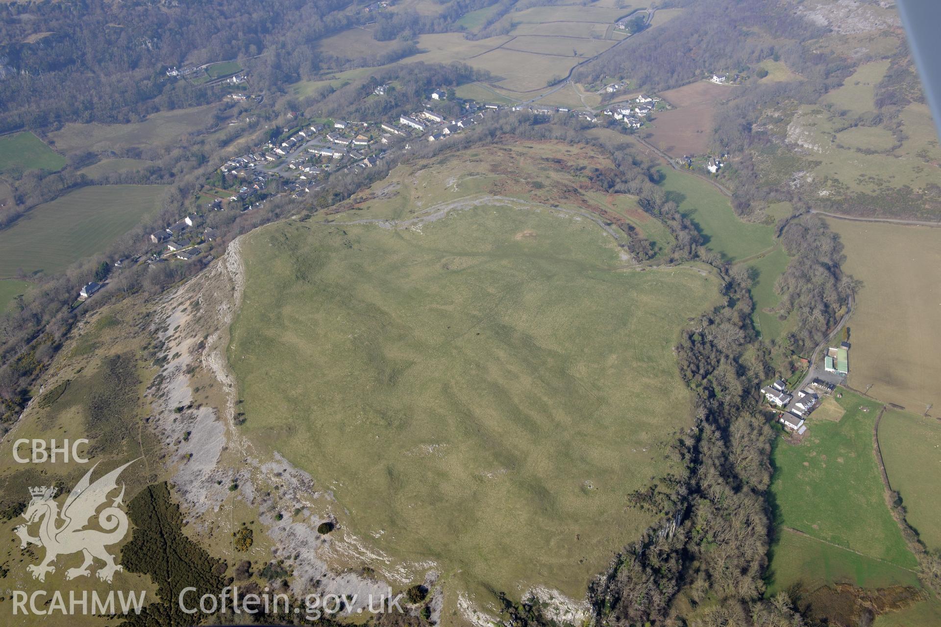 Pen-y-Corddyn-Mawr hillfort, overshadowing the village of Abergele. Oblique aerial photograph taken during the Royal Commission?s programme of archaeological aerial reconnaissance by Toby Driver on 28th February 2013.