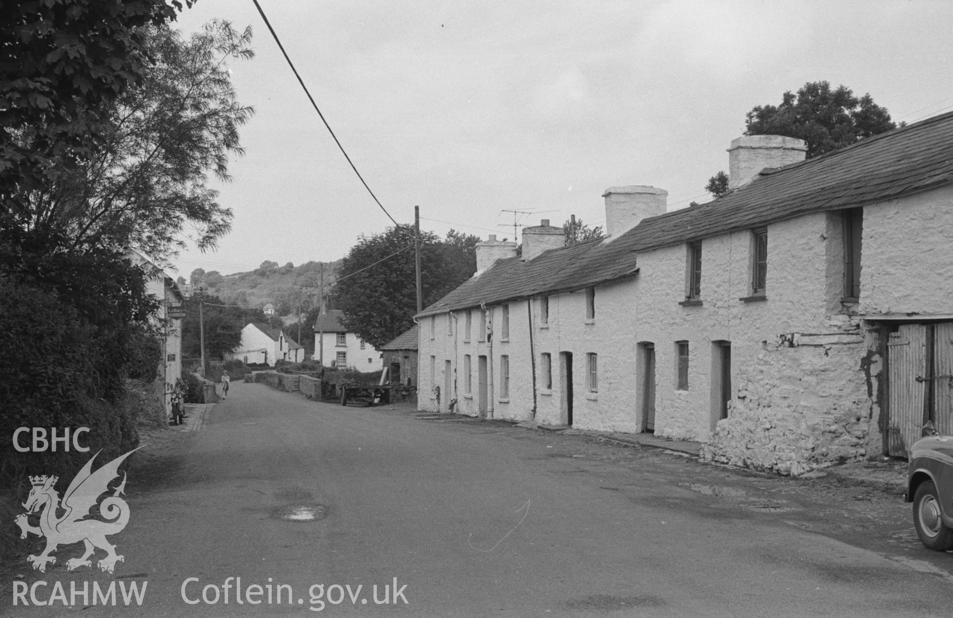 Digital copy of a black and white negative showing view along the main street to the bridge over Cletter Fawr at Talgarreg village. Photographed by Arthur O. Chater in 27th August 1965, from Grid Reference SN 4259 5112, looking north west.