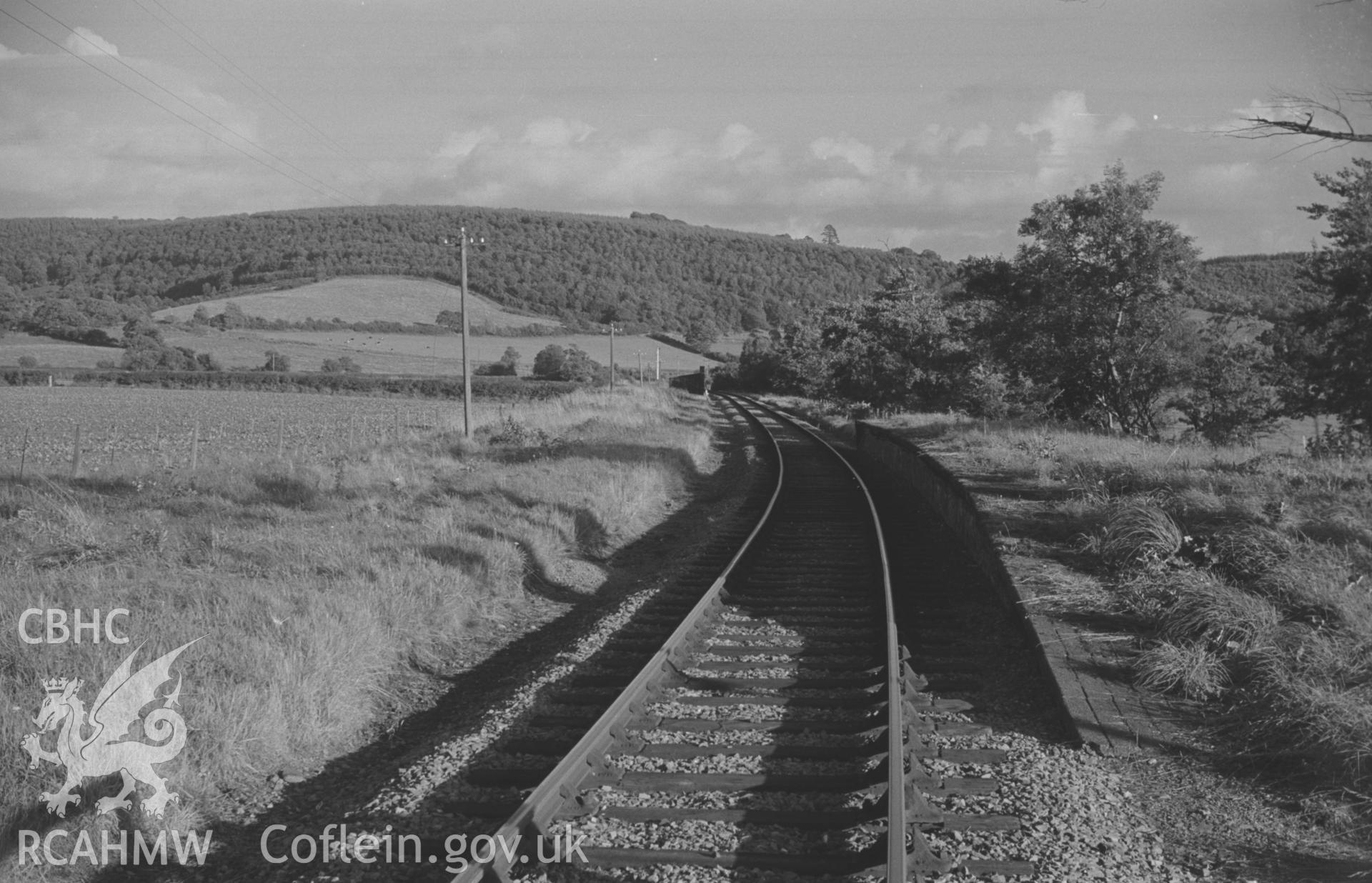 Digital copy of a black and white negative showing Glan Denys Halt on the Aberaeron line. Coed Gwarallt in distance. Photographed by Arthur O. Chater on 4th September 1966 looking south east from Grid Reference SN 582 509.