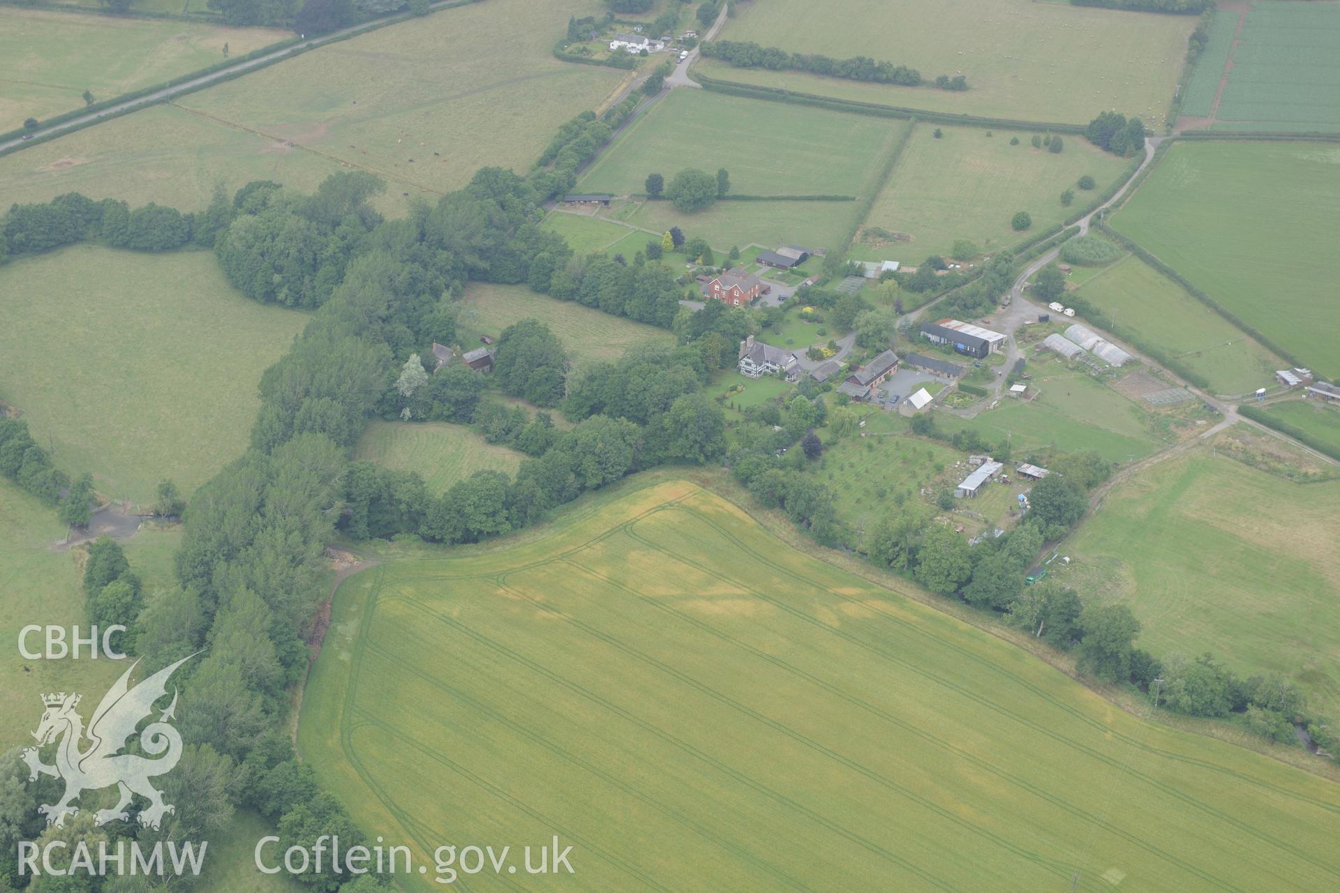 Wegnall farmhouse with the Wegnall cropmarks in the field below, on the Wales-England border south east of Presteigne. Oblique aerial photograph taken during the Royal Commission?s programme of archaeological aerial reconnaissance by Toby Driver on 1st August 2013.