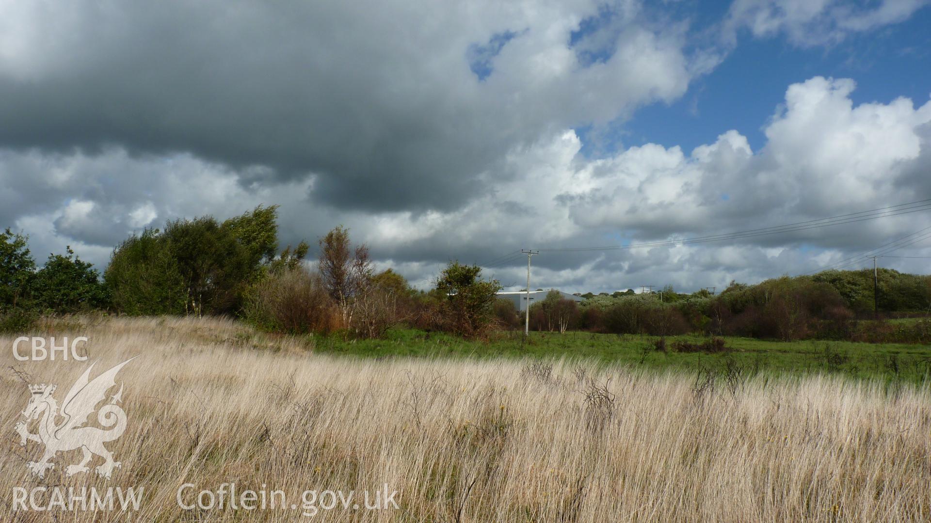 View northeast past the southern edge of Carn Goch (tree/scrub to left of shot). Photographed during Setting Impact Assessment of Land off Phoenix Way, Garngoch Business Village, Swansea, carried out by Archaeology Wales, 2018. Project number P2631.